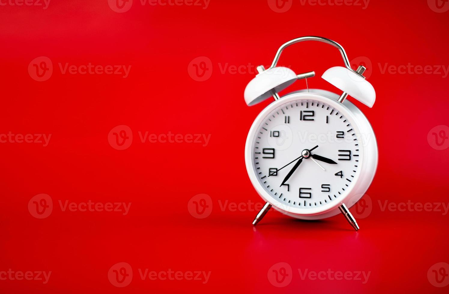 white alarm clock on red background time concept photo