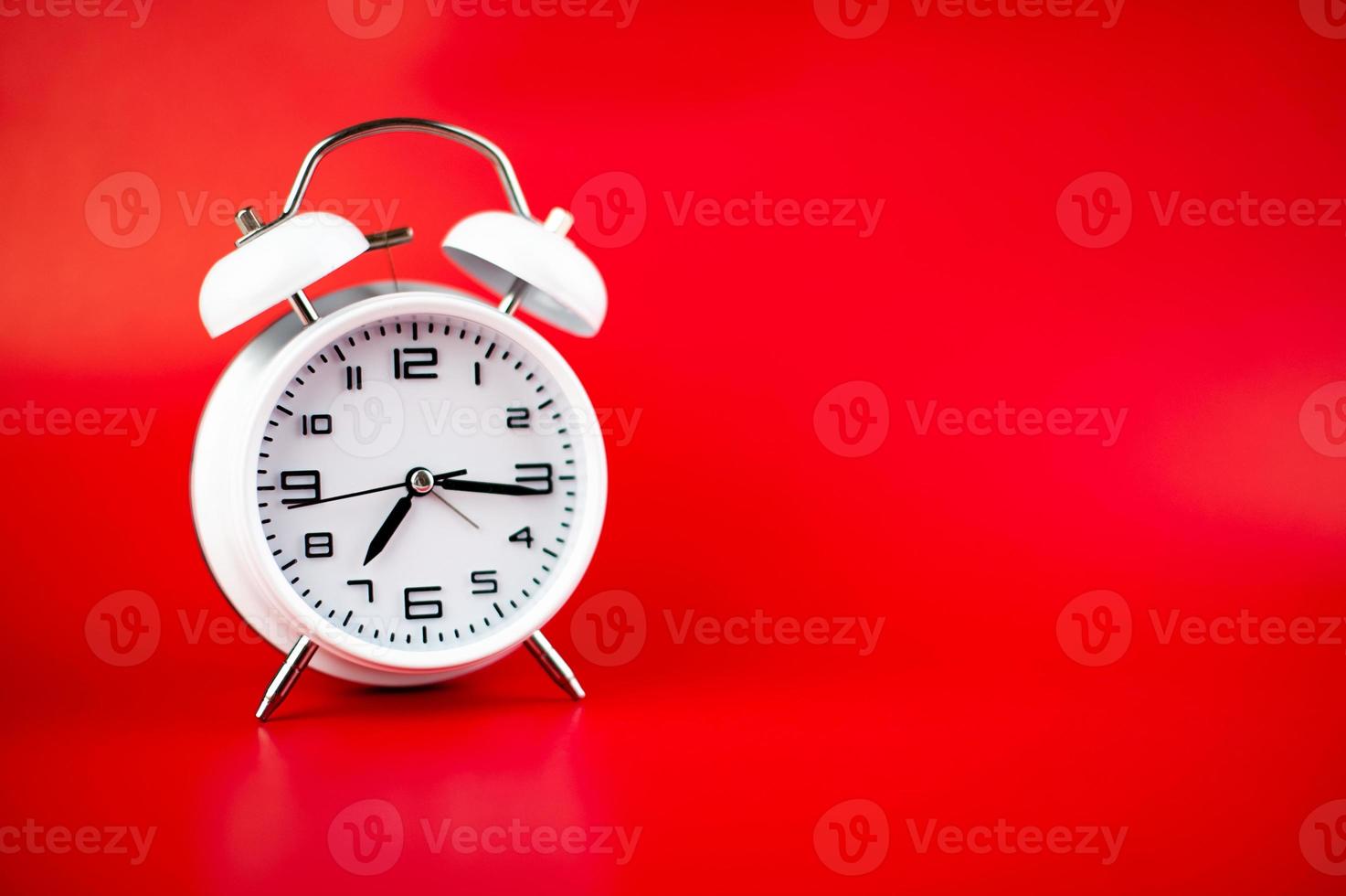 white alarm clock on red background time concept photo