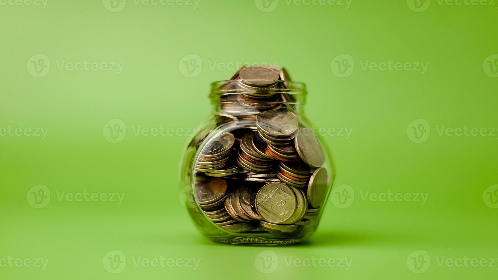 coin money in glass bottle on green scene, money saving concept photo