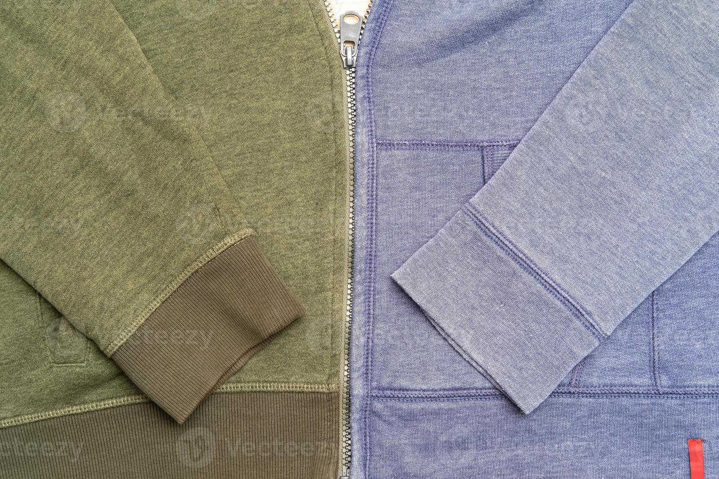 Two different hoodies, green and blue, connected by a single zip. Creative idea. Copy space. Top view. photo