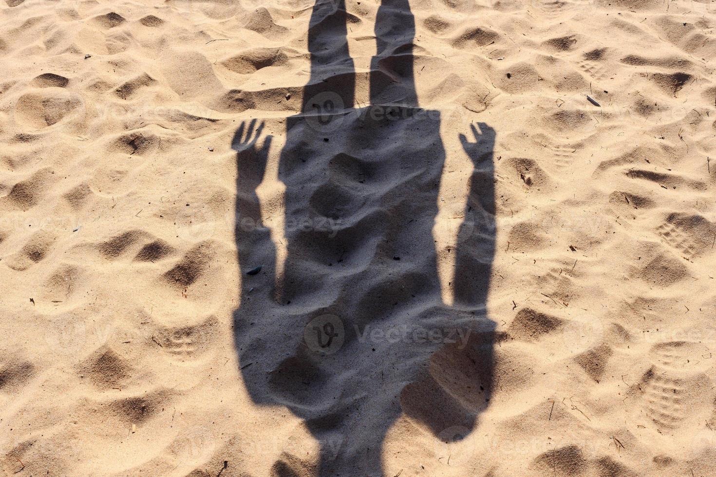 sombra humana sin cabeza en una playa de arena, en un día soleado de verano. foto