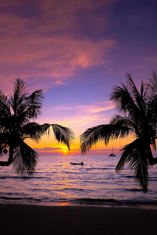 silueta de hermosa puesta de sol en la playa del mar con palmeras para viajar en tiempo de relajación de vacaciones, en el fondo de la naturaleza foto