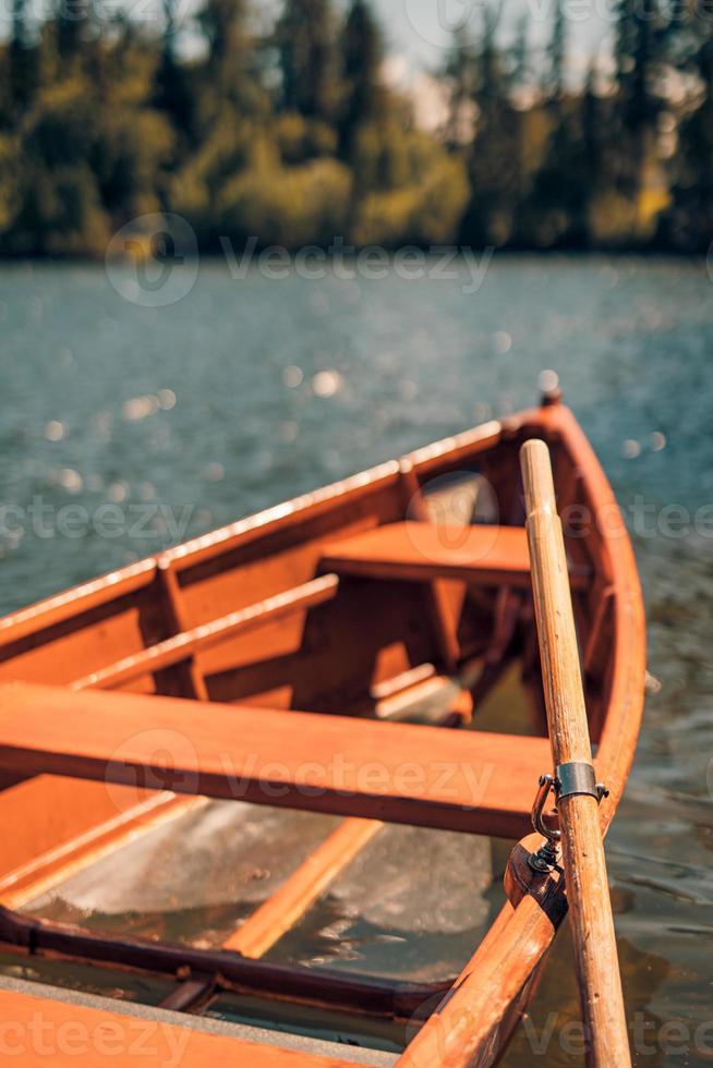 Mountain lake with coniferous forest, wooden boat sunny blue sky, idyllic freedom travel background. Romantic tourist place. National Park High Tatras, Europe. Beautiful nature landscape idyllic view photo