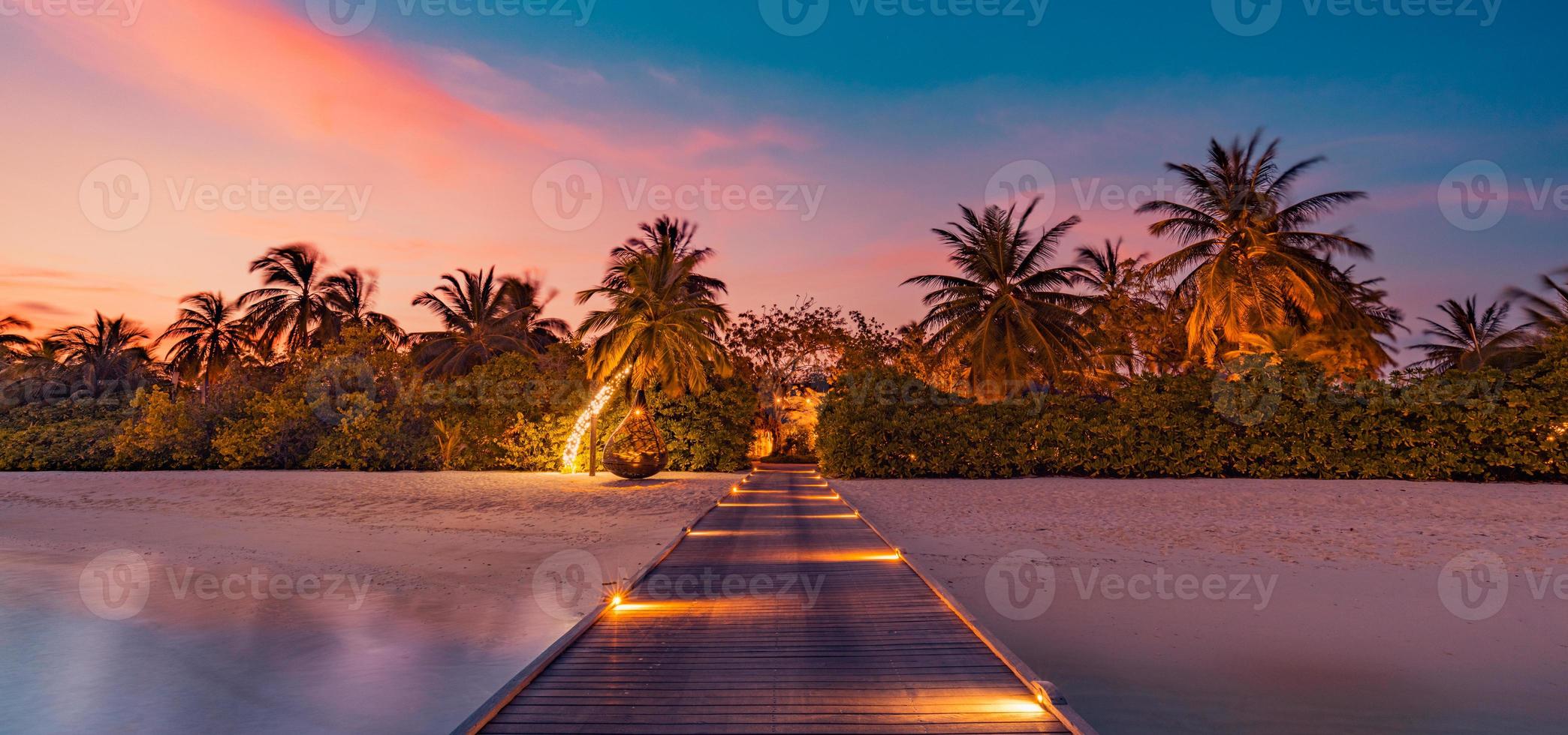 Amazing sunset panorama at Maldives. Luxury resort villas seascape with soft led lights under colorful sky. Beautiful twilight sky and colorful clouds. Beautiful beach background for vacation holiday photo