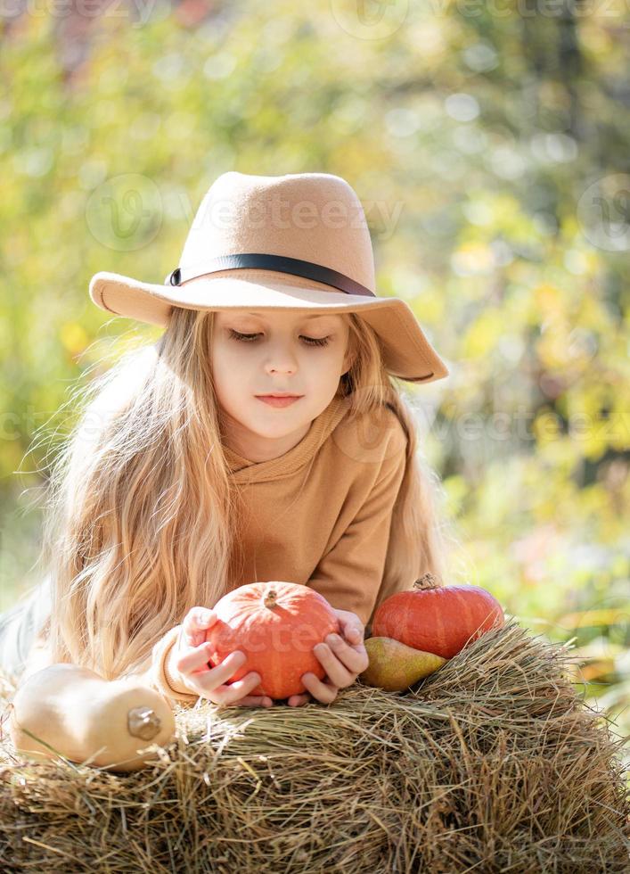 niña en el heno con calabazas foto