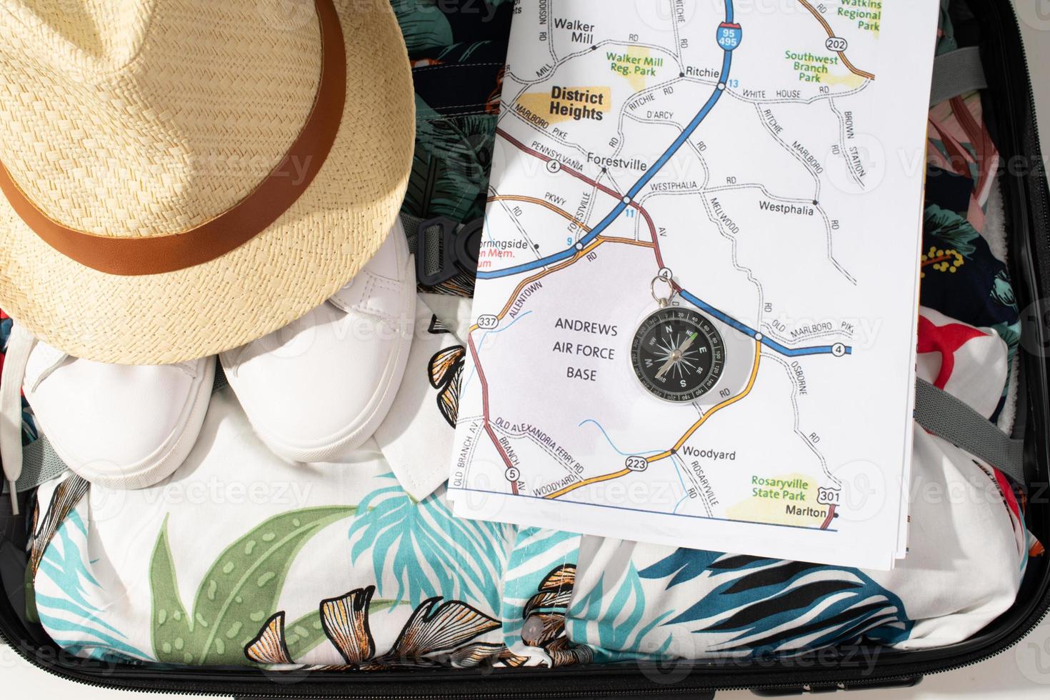 traveler accessories in bag, map, hat, compass over hawaiian shirts photo