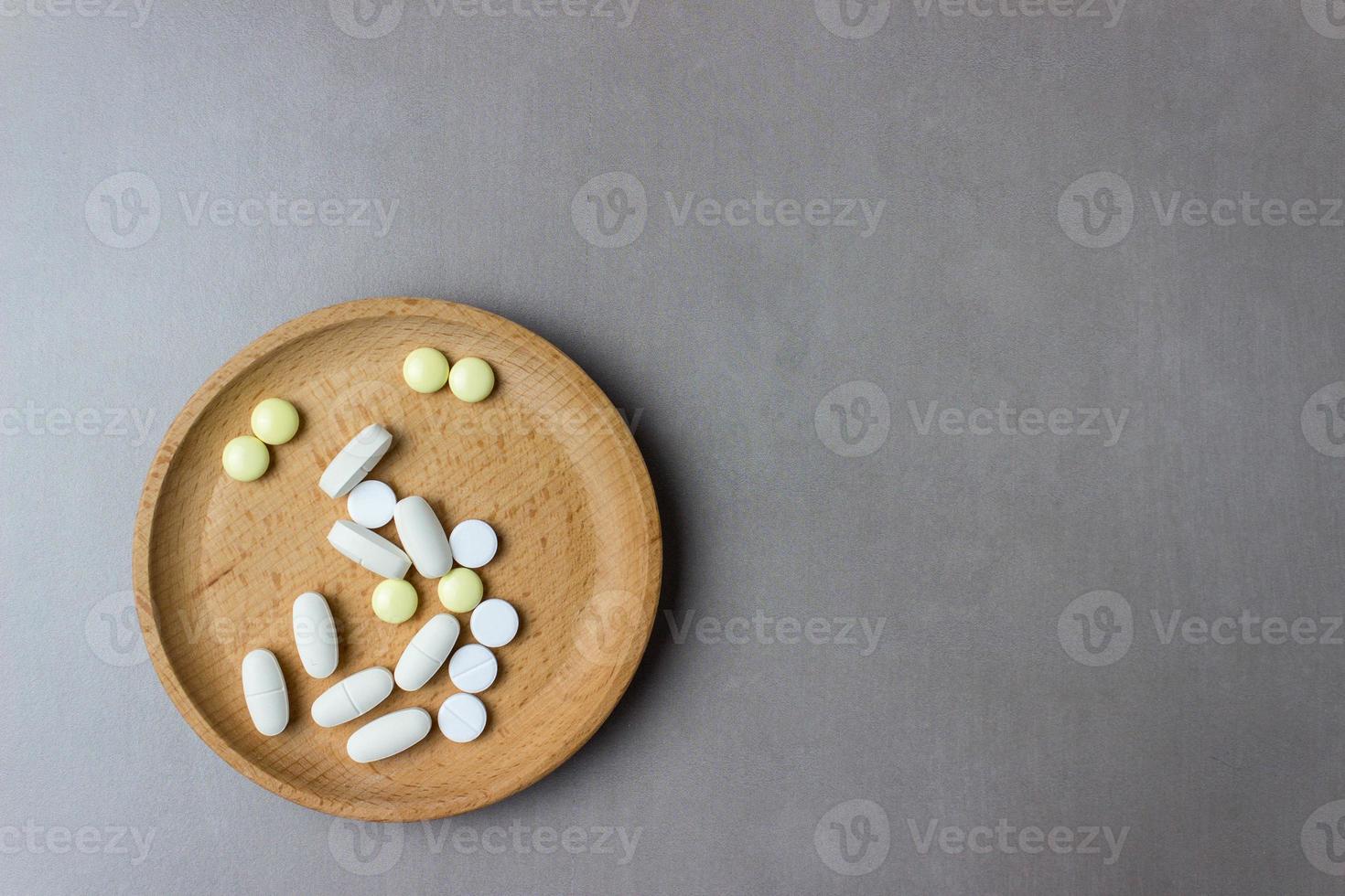 un puñado de pastillas en un plato de madera. el concepto de medicina, tratamiento. vista superior. foto