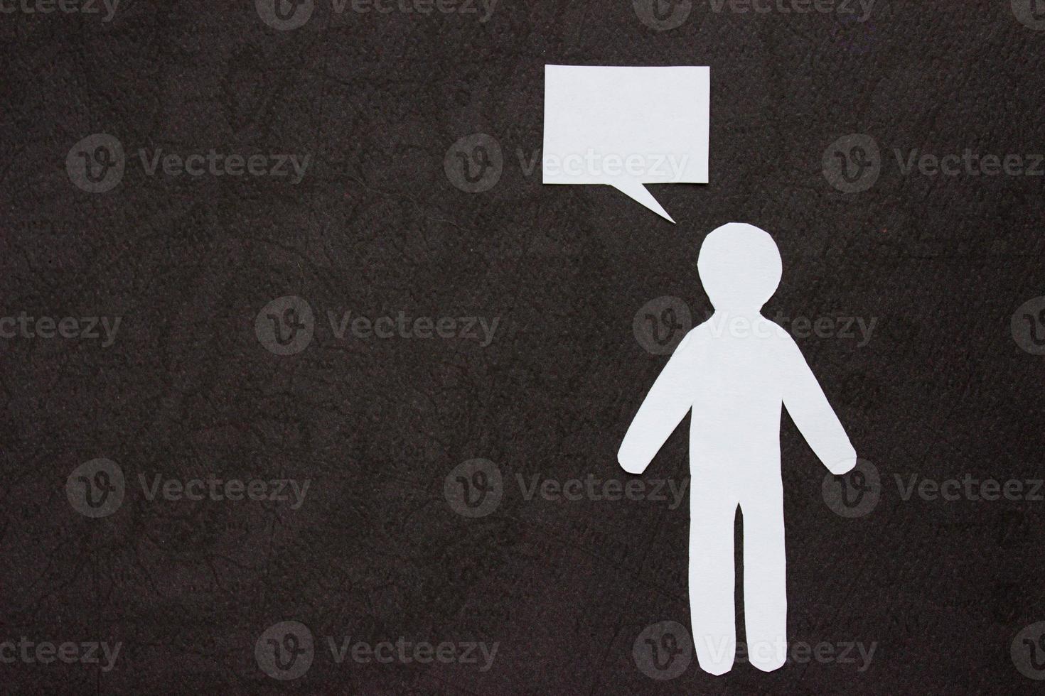 Silhouette of man cut out of white paper. With speech-bubble. On right side of the photo on a black background with copy space
