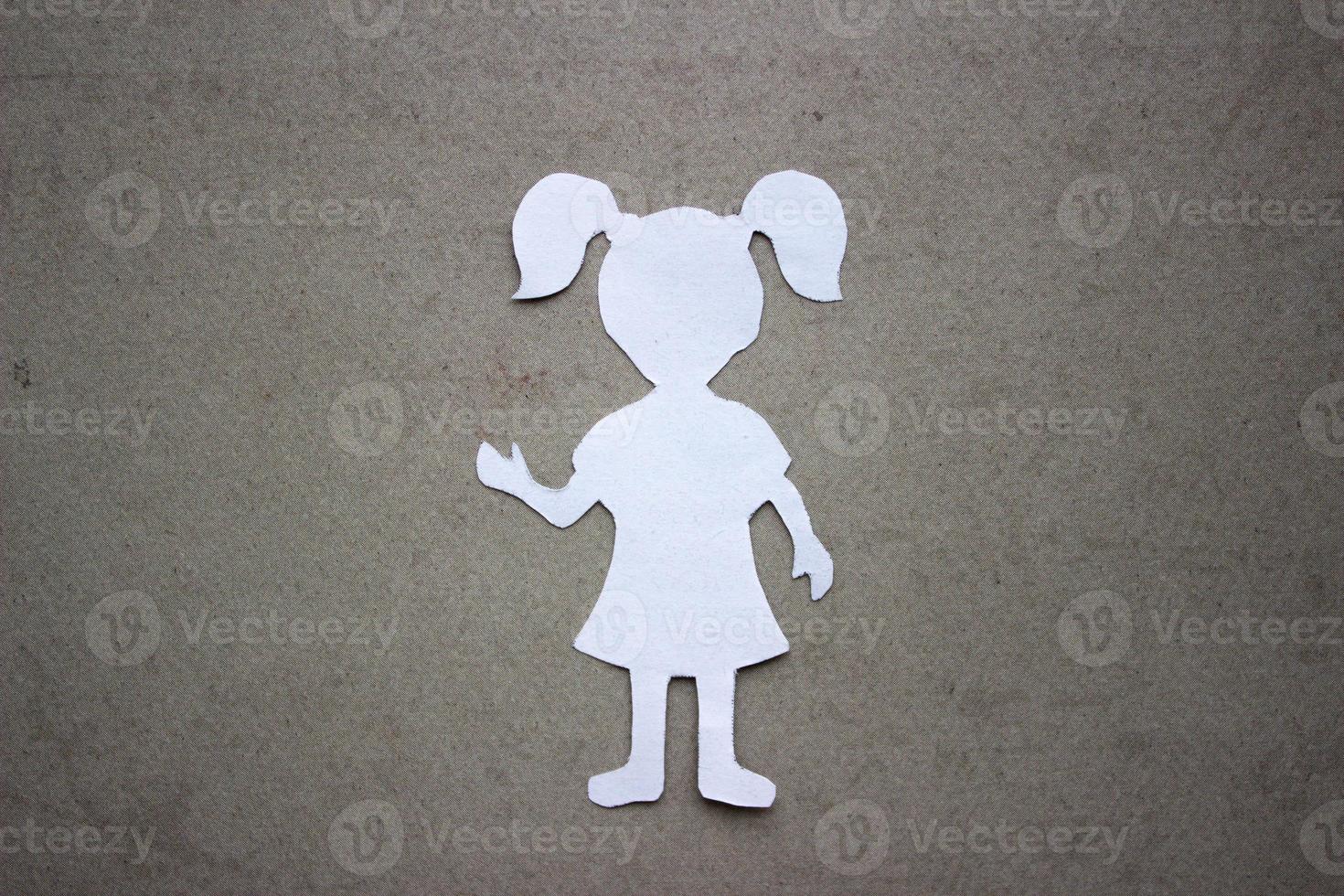 The form of a girl in a dress and with ponytails made of white paper, cut by hand. In the center of the photo