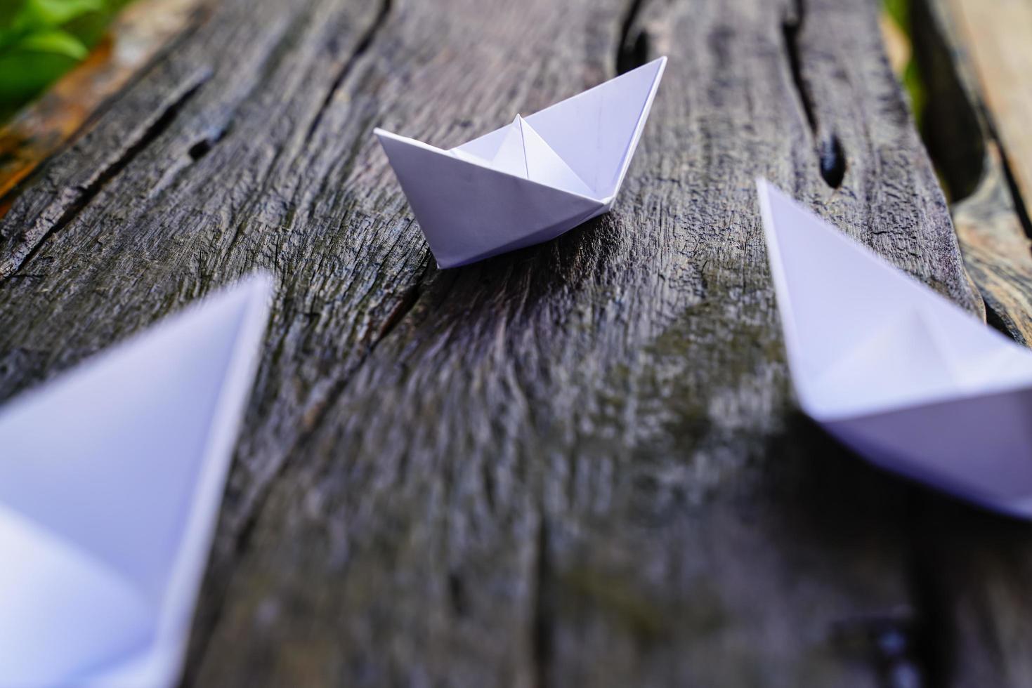 origami, barco de papel blanco aislado en un piso de madera. Los barcos de papel significan caminar. sentimiento de libertad liderazgo foto