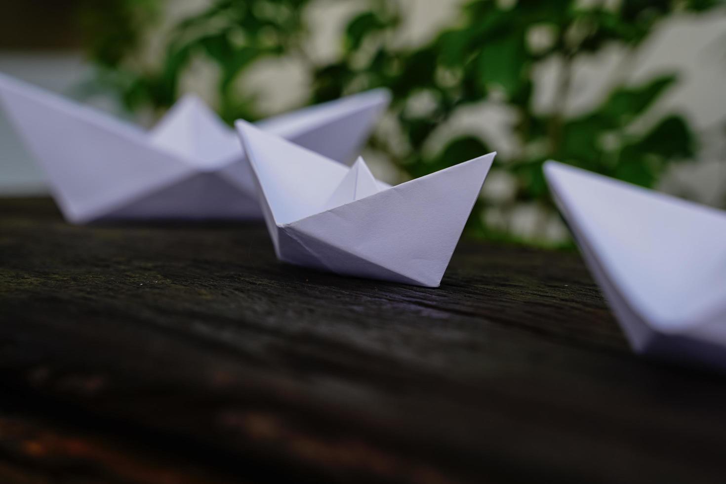 Origami, white paper boat isolated on a wooden floor.  Paper boats mean walking.  feeling of freedom  leadership photo