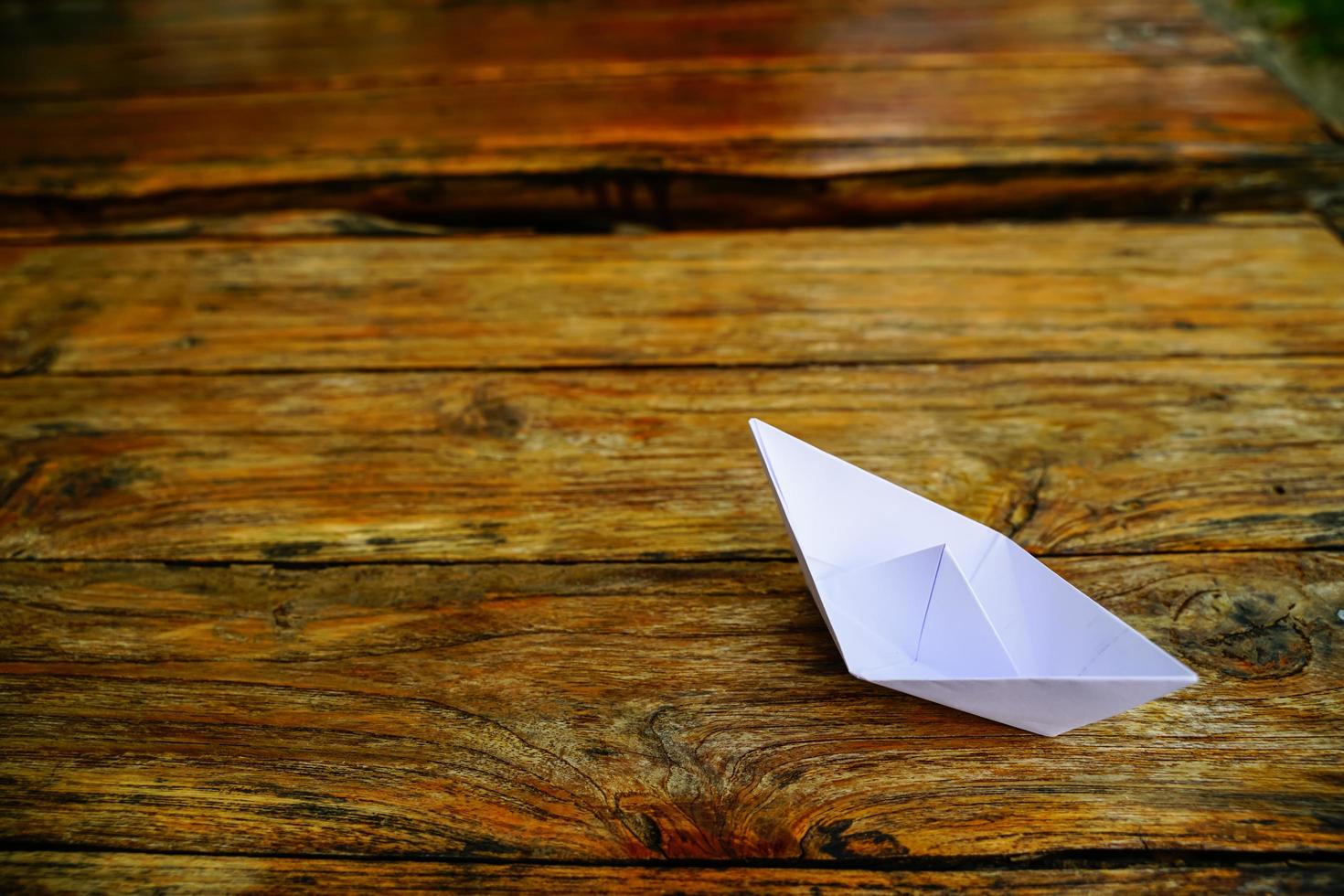 origami, barco de papel blanco aislado en un piso de madera. Los barcos de papel significan caminar. sentimiento de libertad liderazgo foto