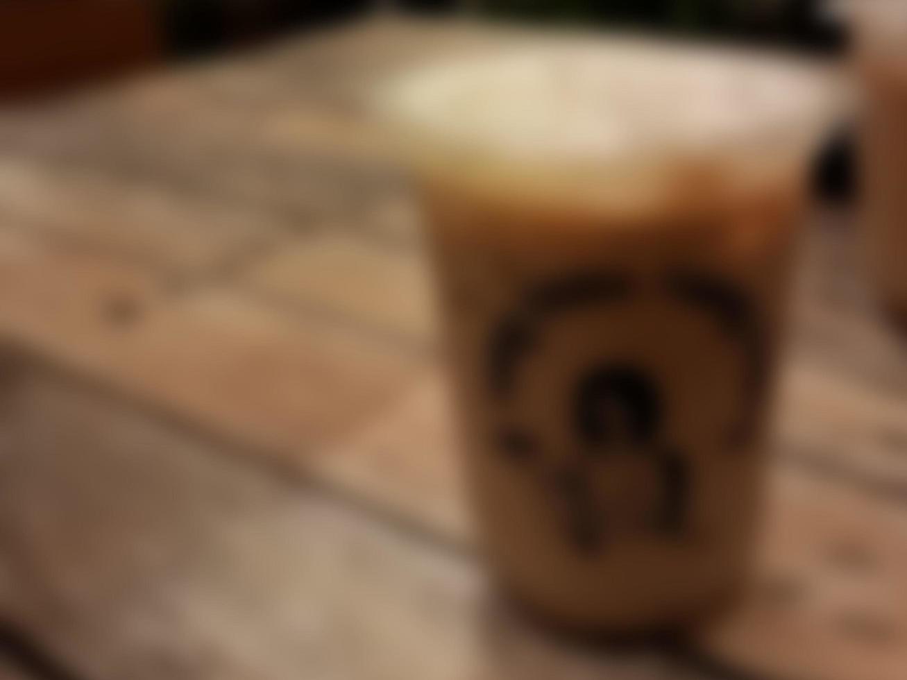 Defocused abstract background of a glass of milk coffee served on a wooden table photo