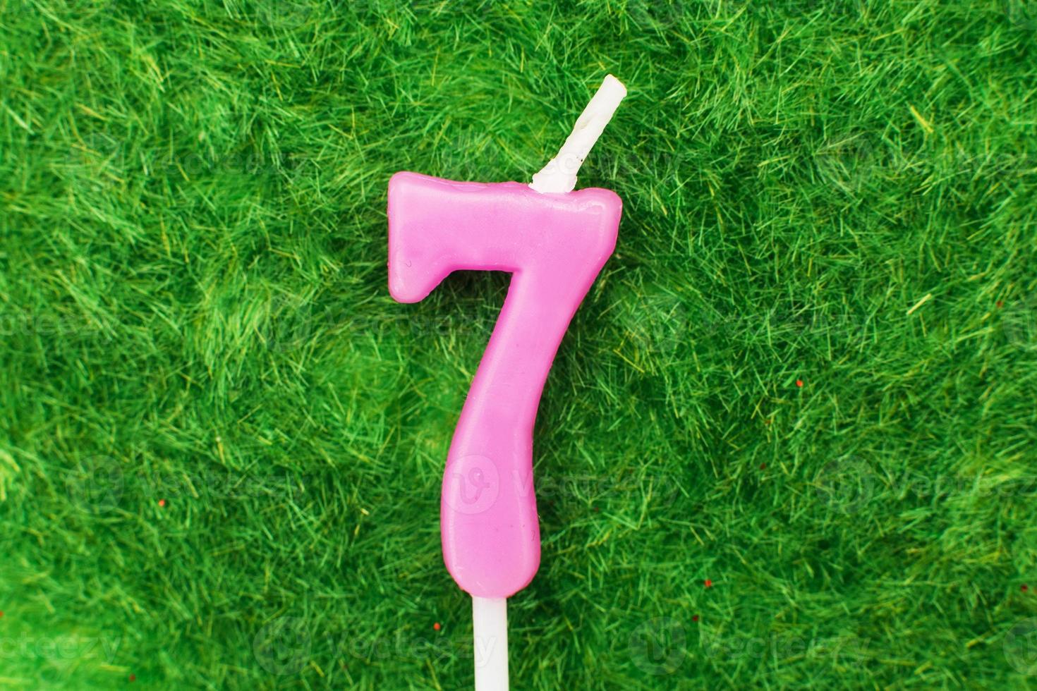 candle in the form of number 7 on the green grass background, a place for a greeting text photo