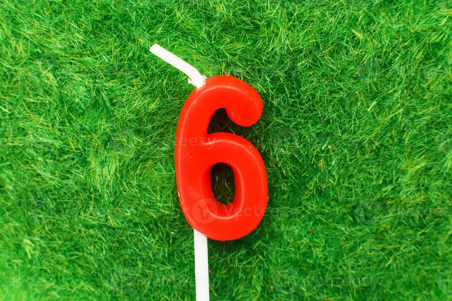 candle in the form of number 6 on the green grass background, a place for a greeting text photo