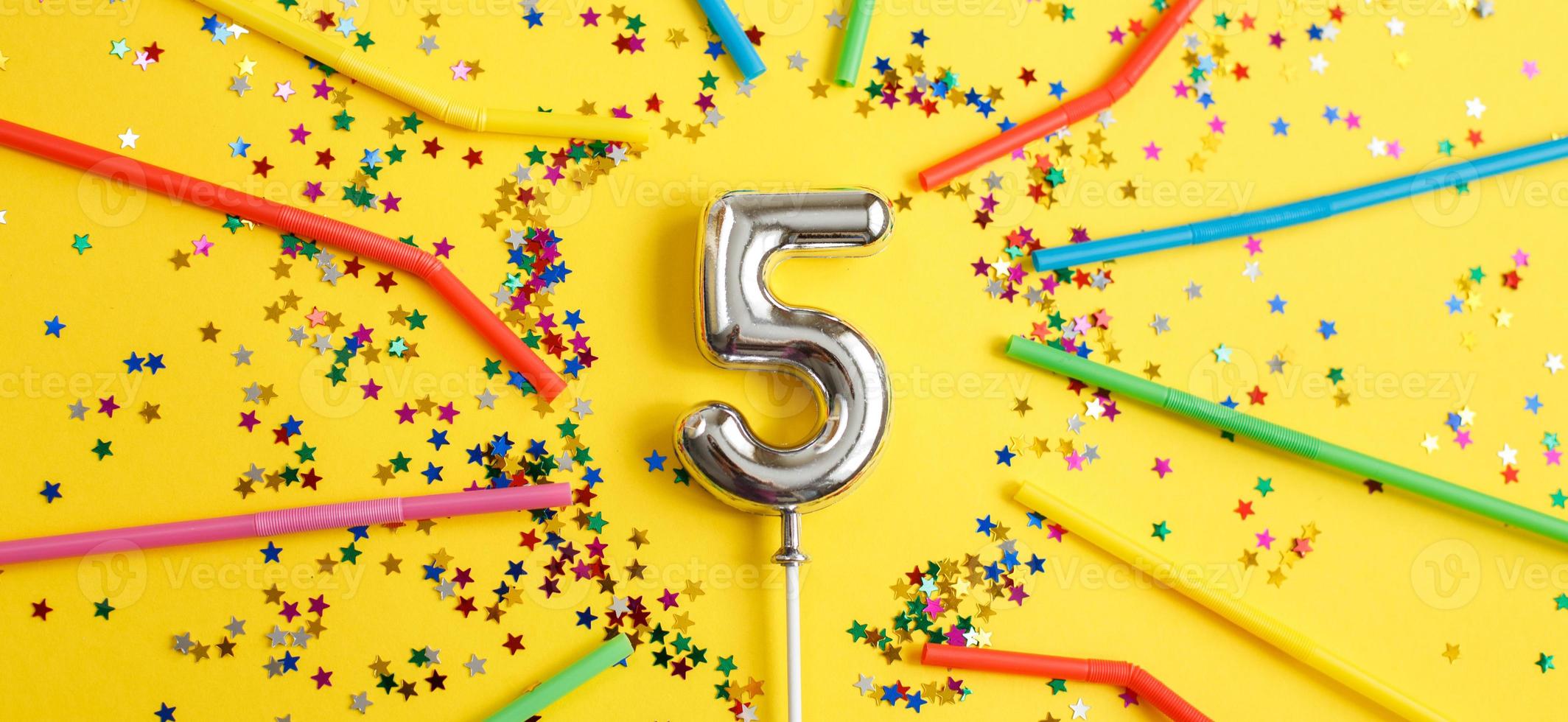 five years birthday party. number five with in form of stars and drinking straws on yellow background photo