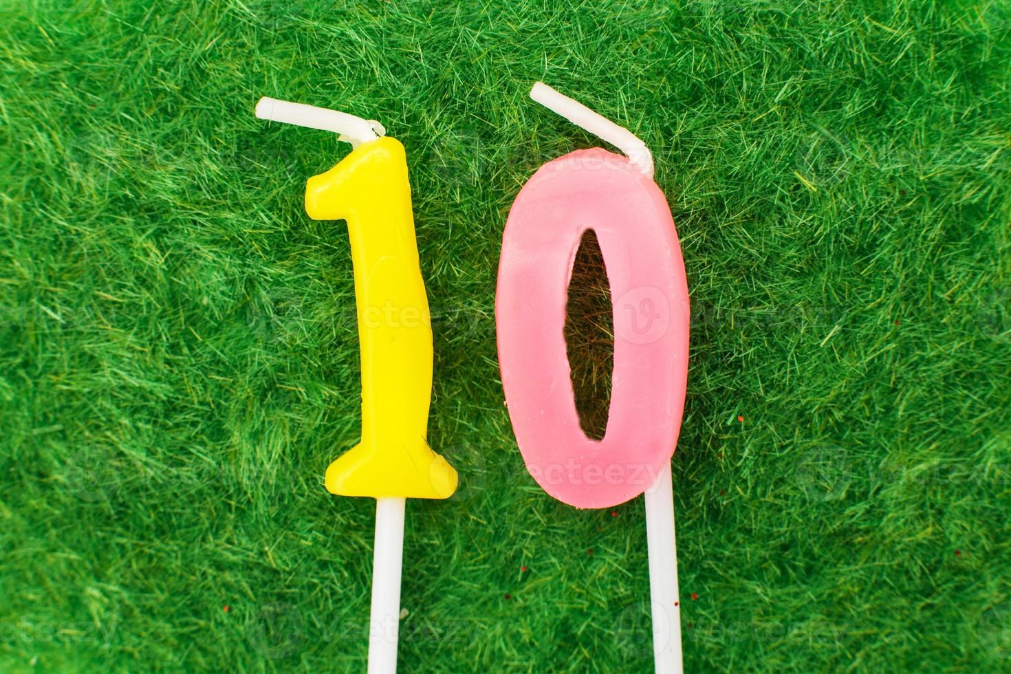 candle in the form of number 10 on the green grass background, a place for a greeting text photo