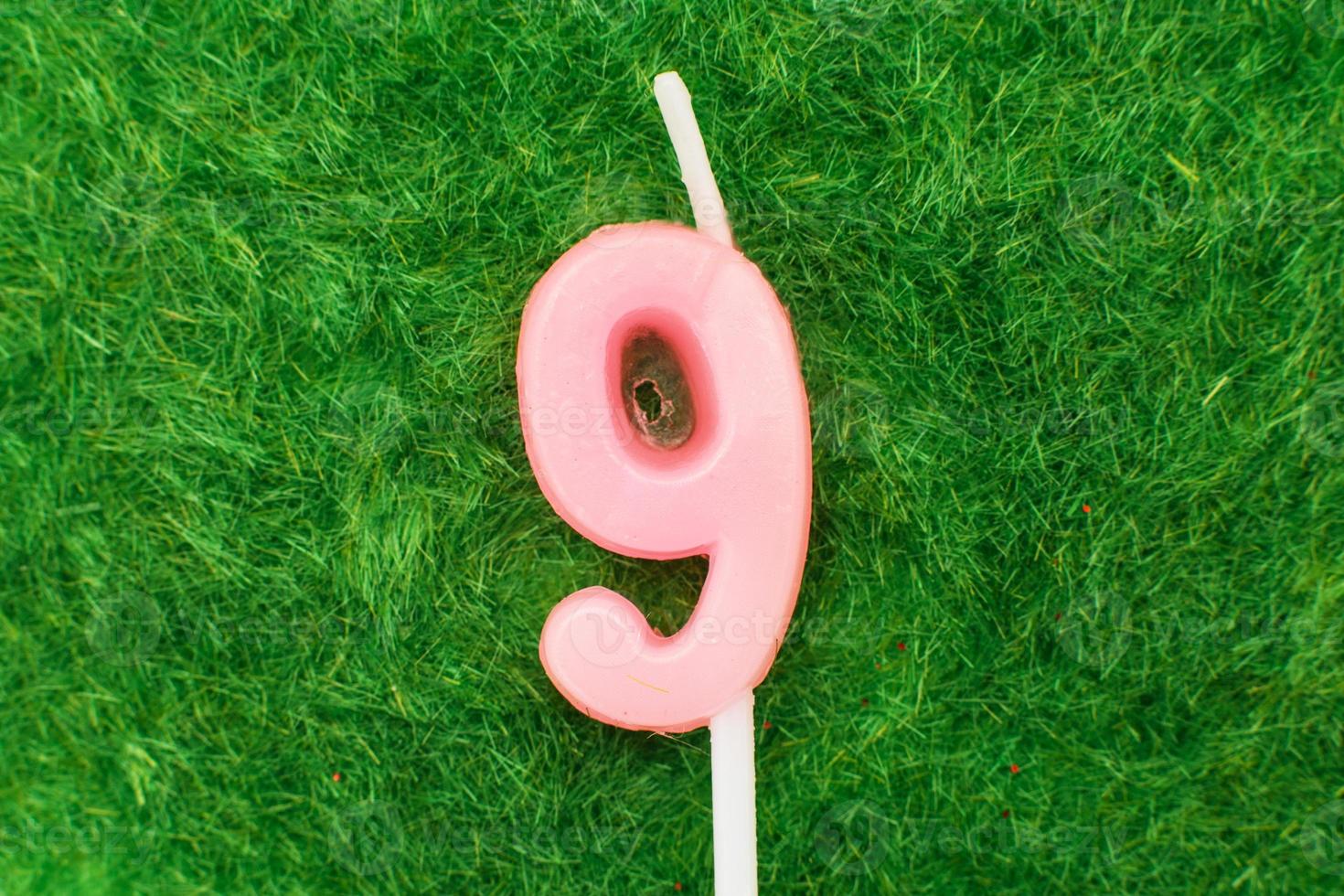 candle in the form of number 9 on the green grass background, a place for a greeting text photo