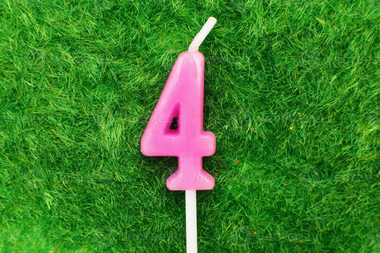 candle in the form of number 4 on the green grass background, a place for a greeting text photo