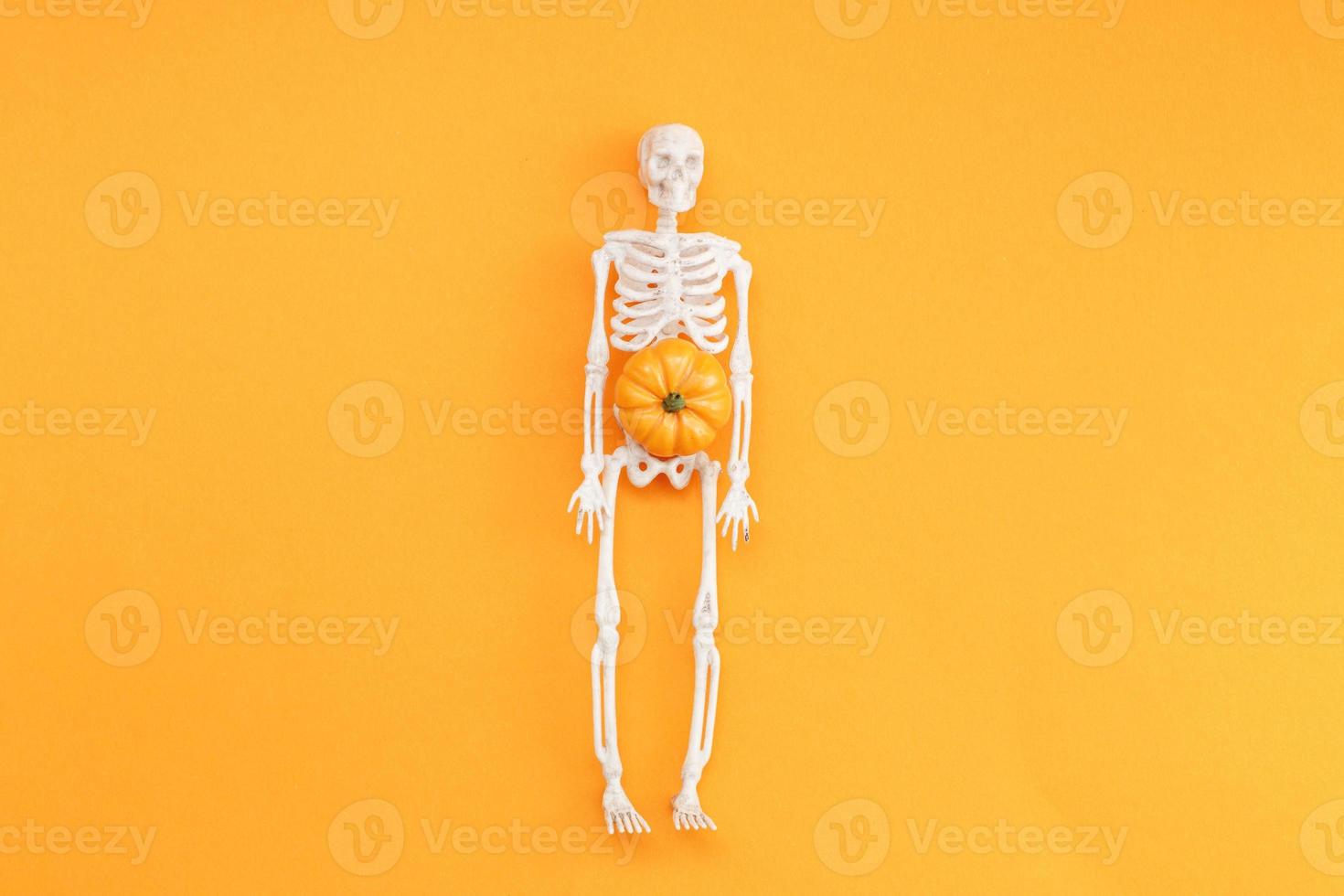 skeleton with pumpkin on orange background. halloween concept photo