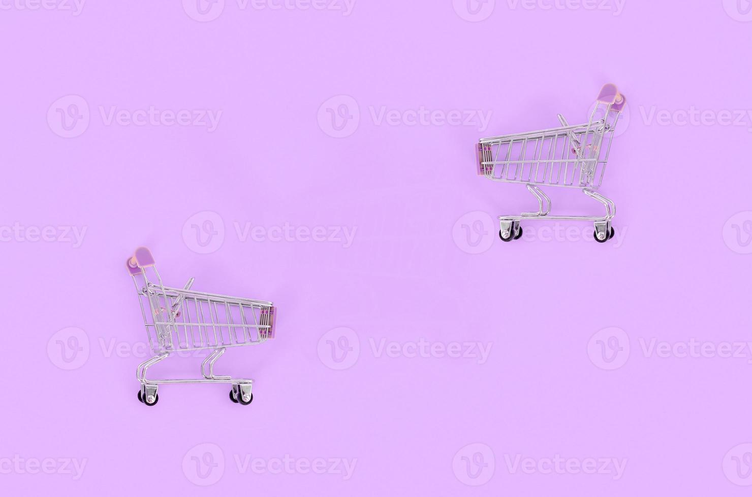 Shopping addiction, shopping lover or shopaholic concept. Small empty shopping cart lies on a pastel colored paper background. Flat lay minimal composition, top view photo