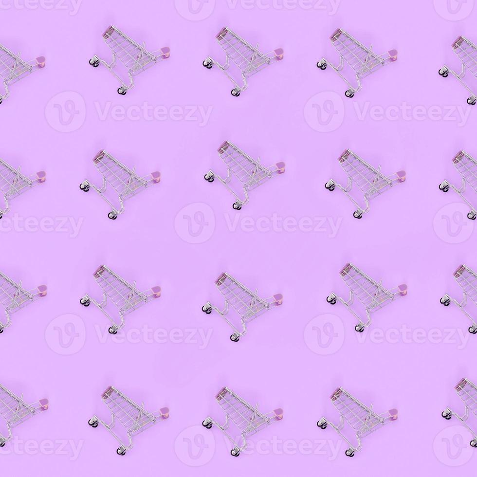 Shopping addiction, shopping lover or shopaholic concept. Many small empty shopping carts perform a pattern on a pastel colored paper background. Flat lay composition, top view photo