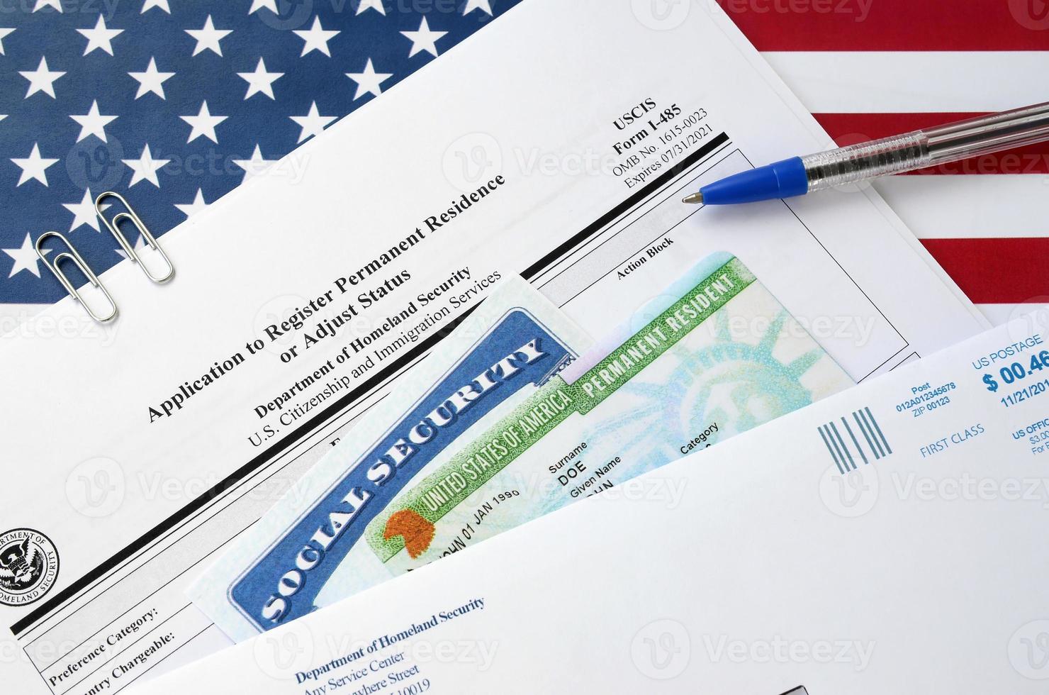 I-485 Application to register permanent residence or adjust status form and green card from dv-lottery with social security number lies on United States flag with USCIS envelope photo