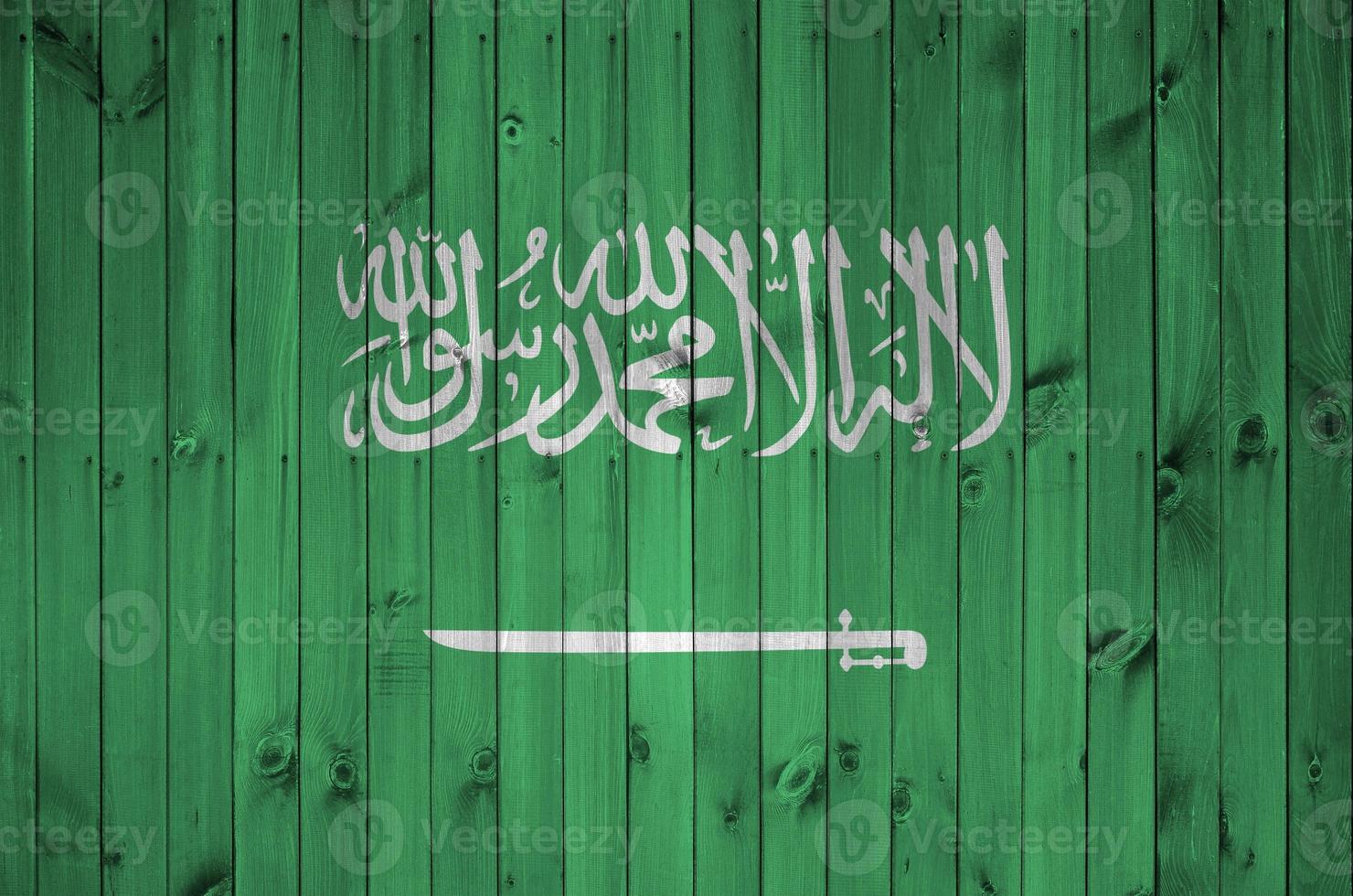 Saudi Arabia flag depicted in bright paint colors on old wooden wall. Textured banner on rough background photo