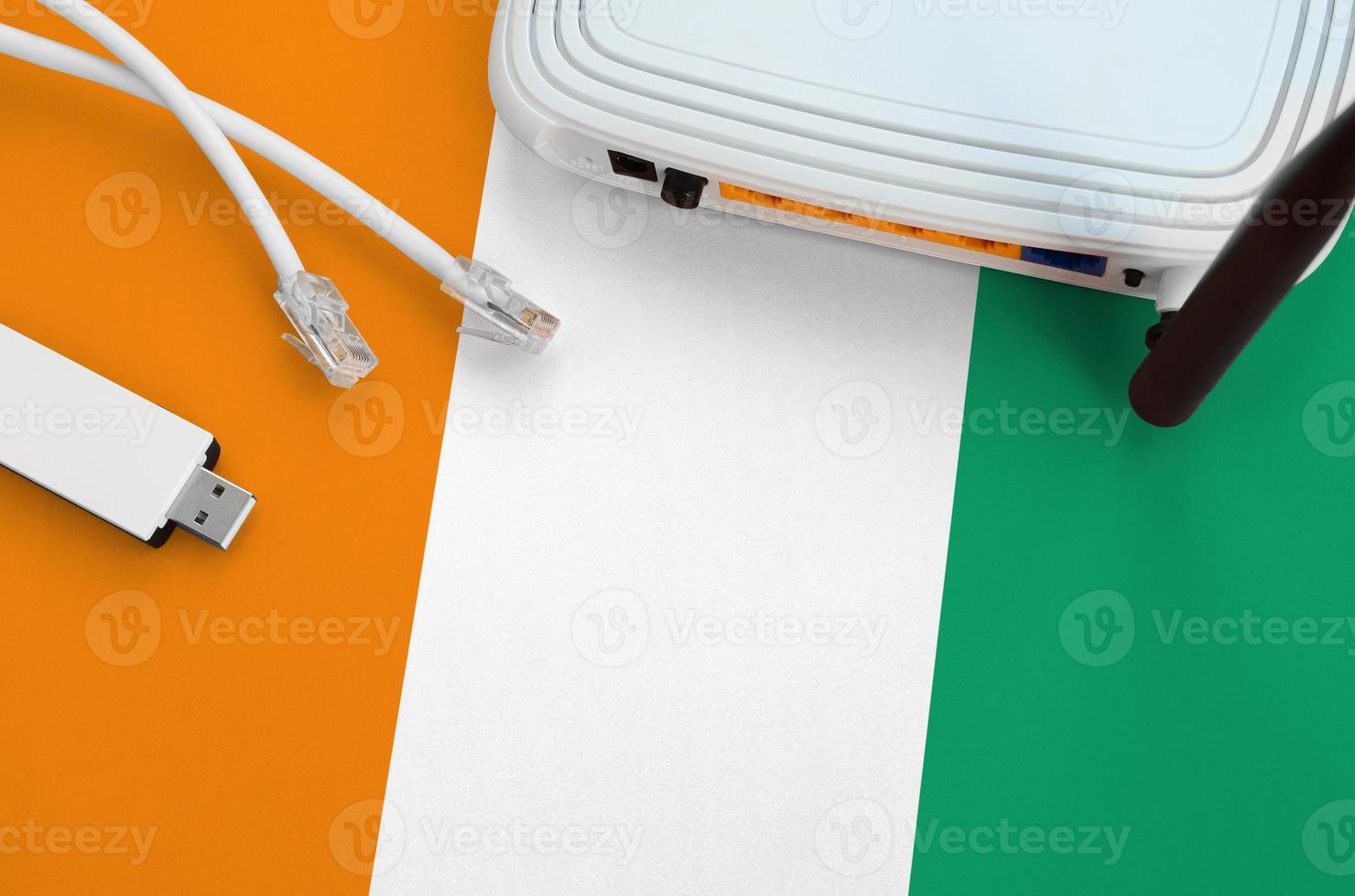 Ivory Coast flag depicted on table with internet rj45 cable, wireless usb wifi adapter and router. Internet connection concept photo