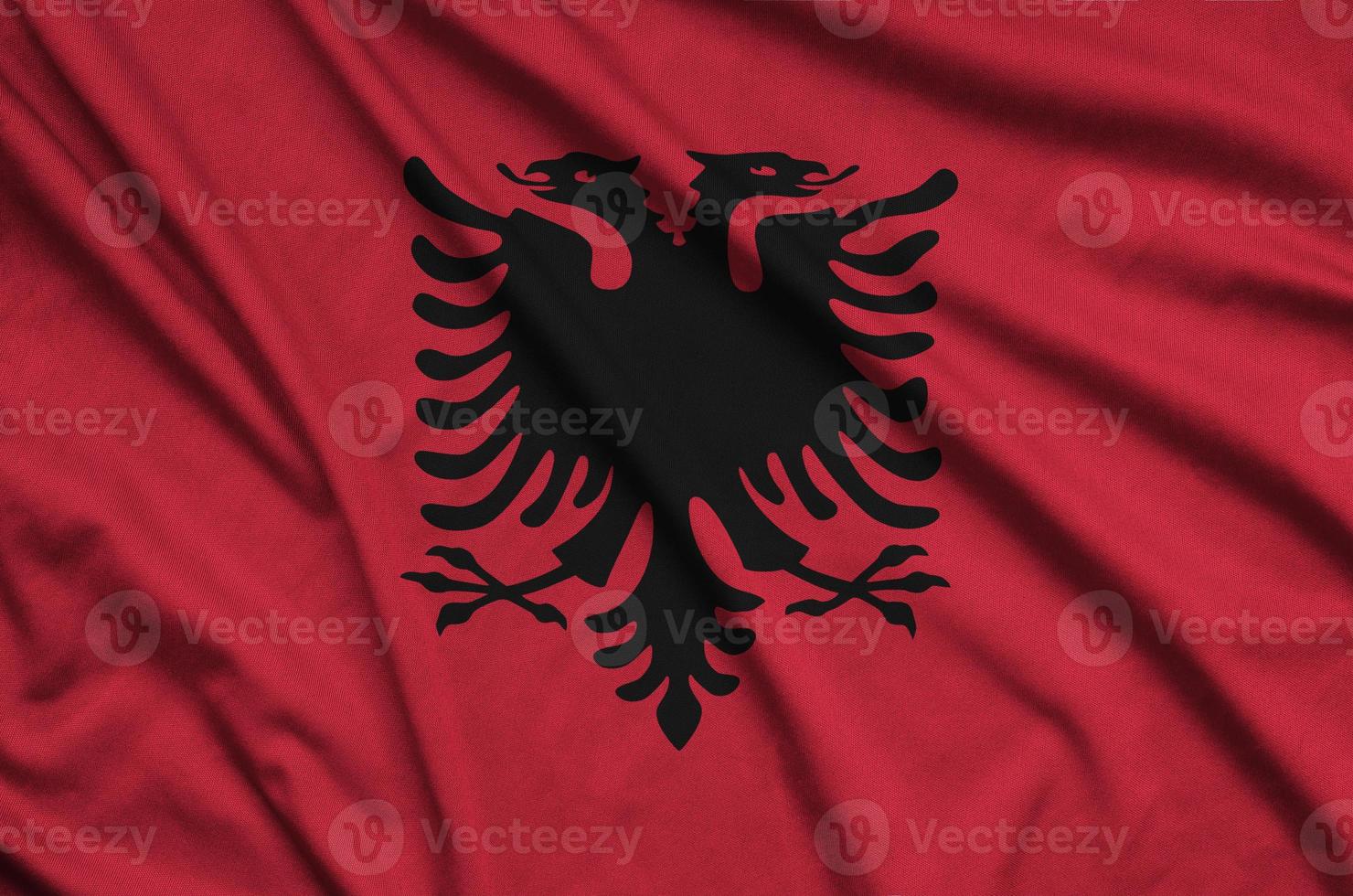 Albania flag is depicted on a sports cloth fabric with many folds. Sport team banner photo