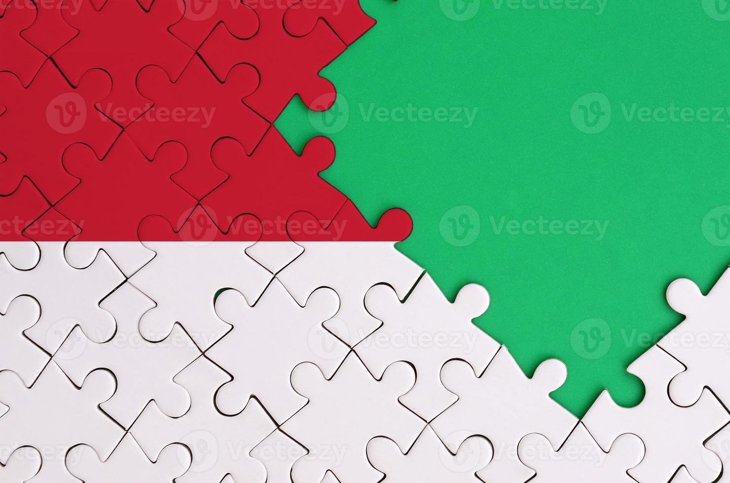 Indonesia flag is depicted on a completed jigsaw puzzle with free green copy space on the right side photo