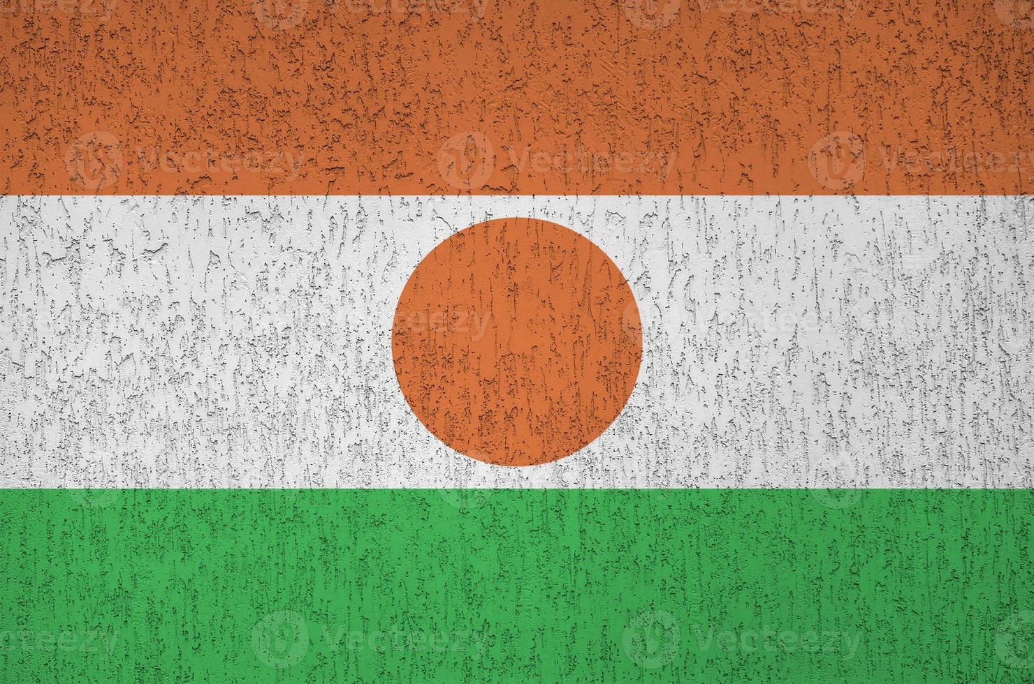 Niger flag depicted in bright paint colors on old relief plastering wall. Textured banner on rough background photo