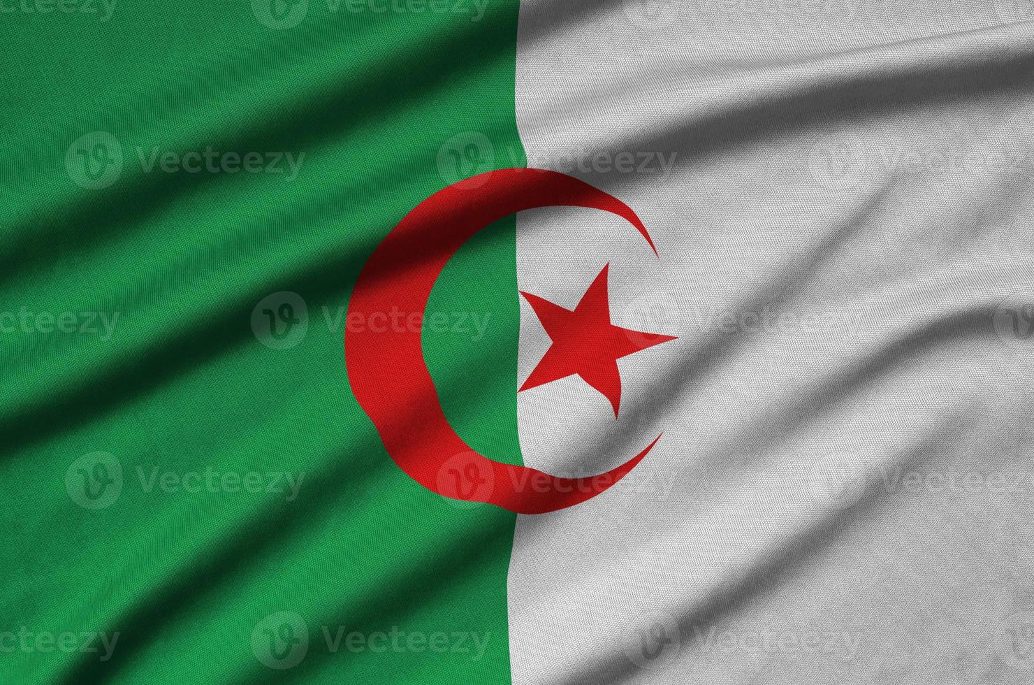 Algeria flag is depicted on a sports cloth fabric with many folds. Sport team banner photo