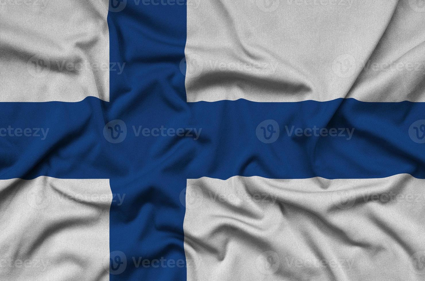 Finland flag is depicted on a sports cloth fabric with many folds. Sport team banner photo