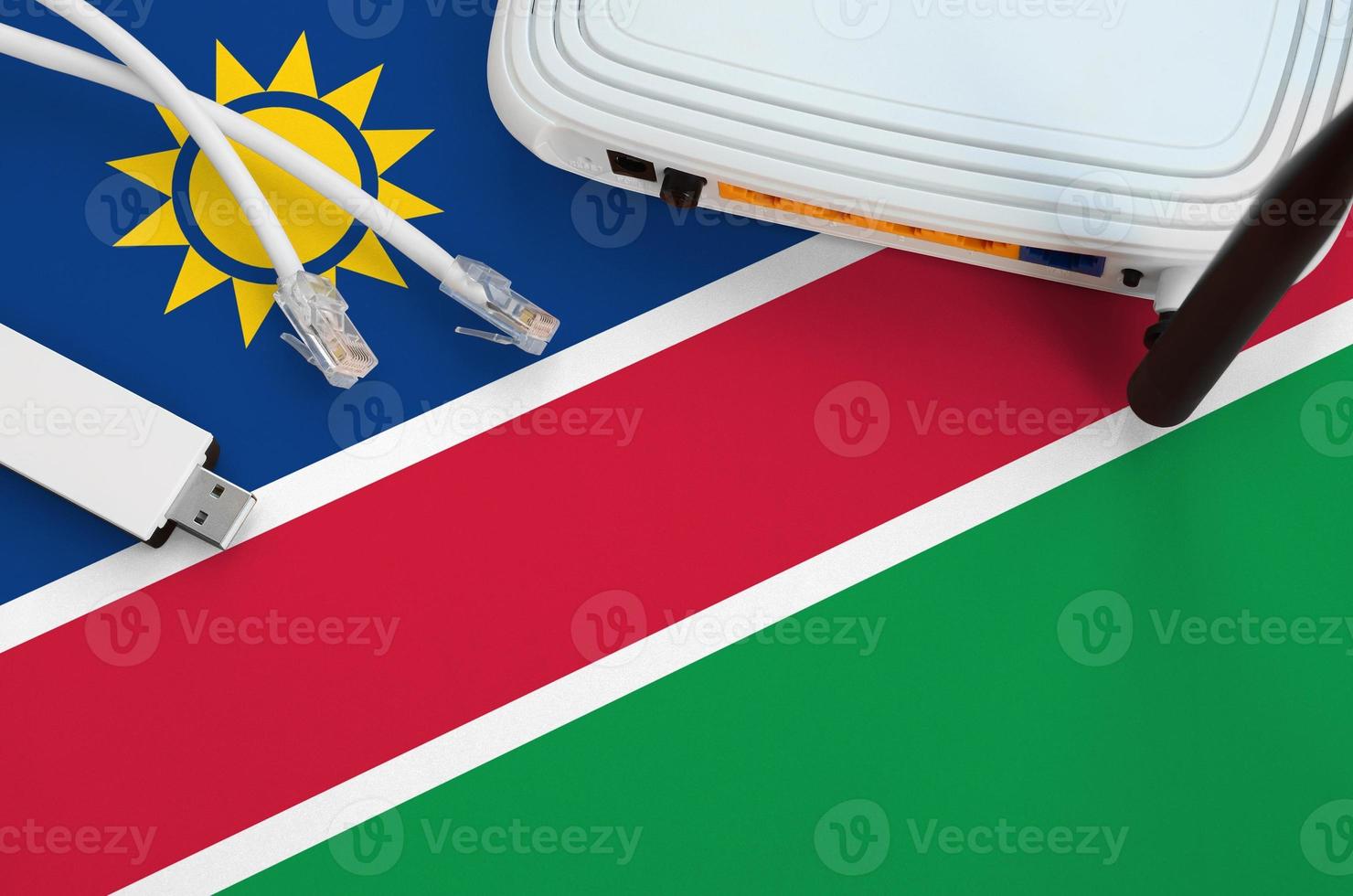 Namibia flag depicted on table with internet rj45 cable, wireless usb wifi adapter and router. Internet connection concept photo