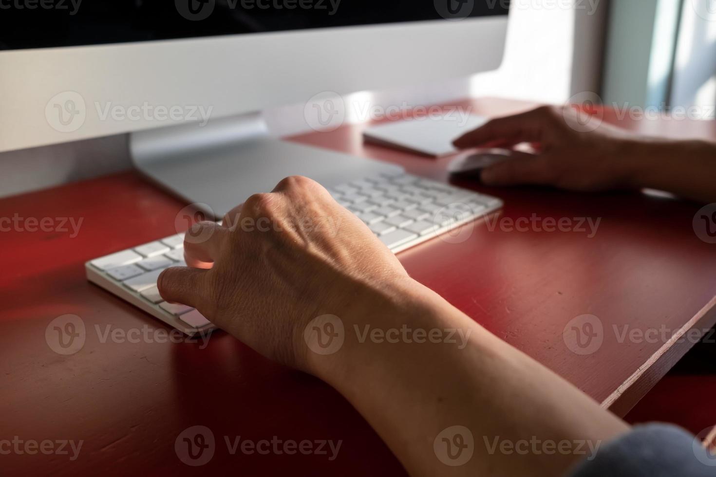 Woman works with a computer, one hand is on the keyboard, the other on the mouse. Remote work. Contemporary workplace and lifestyle. photo