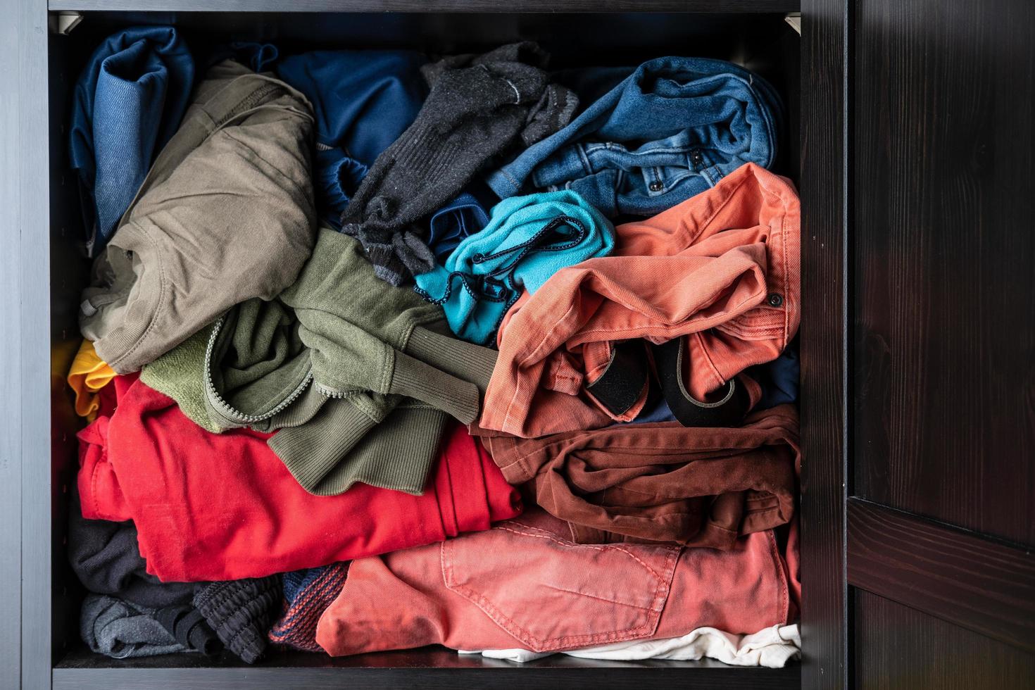 Variety of brightly colored clothes lie casually on a shelf in a closet. photo