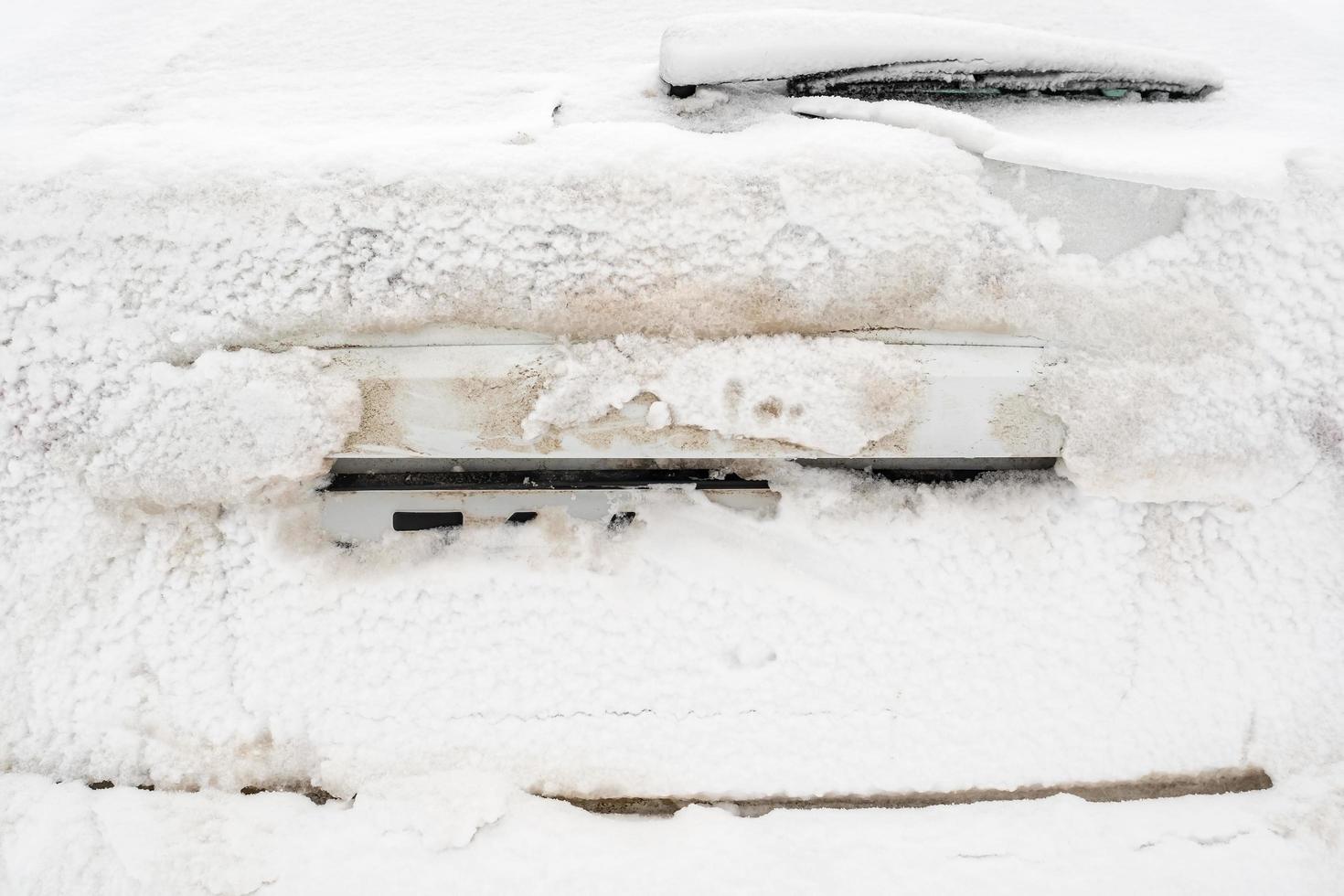 Snow-covered car number and trunk door, outdoors, on a winter day. photo