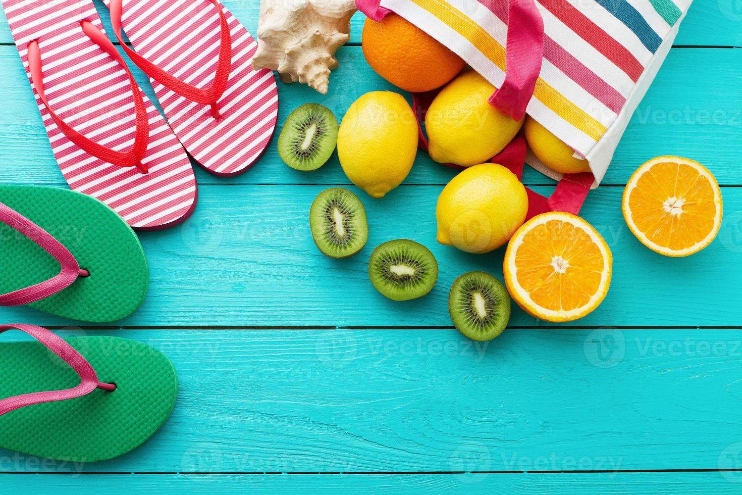 Summer fun time and fruits on blue wooden background. Orange, lemon fruit in bag and flip flops. Top view and copy space photo