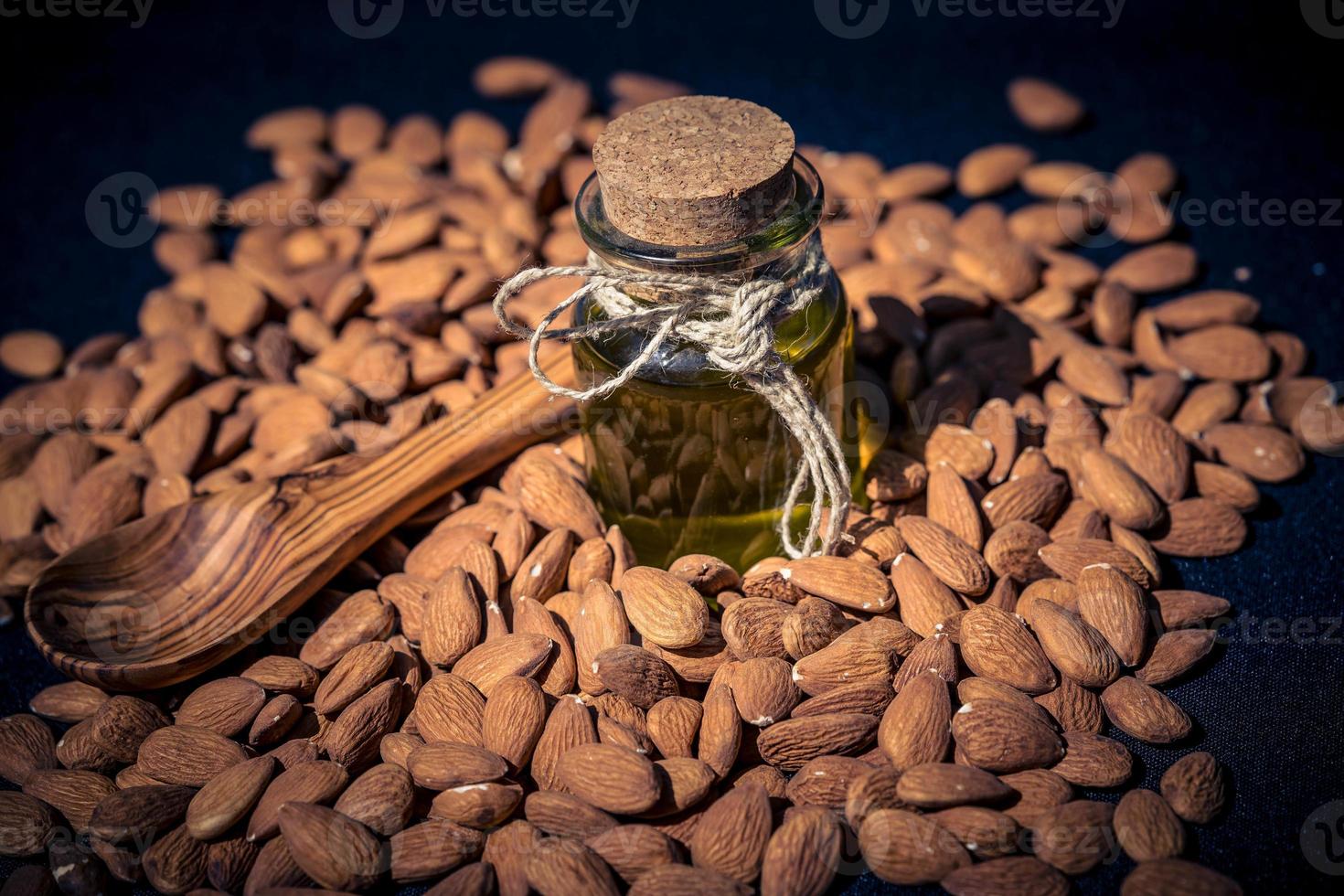 un montón de almendras y un vaso con aceite de almendras foto