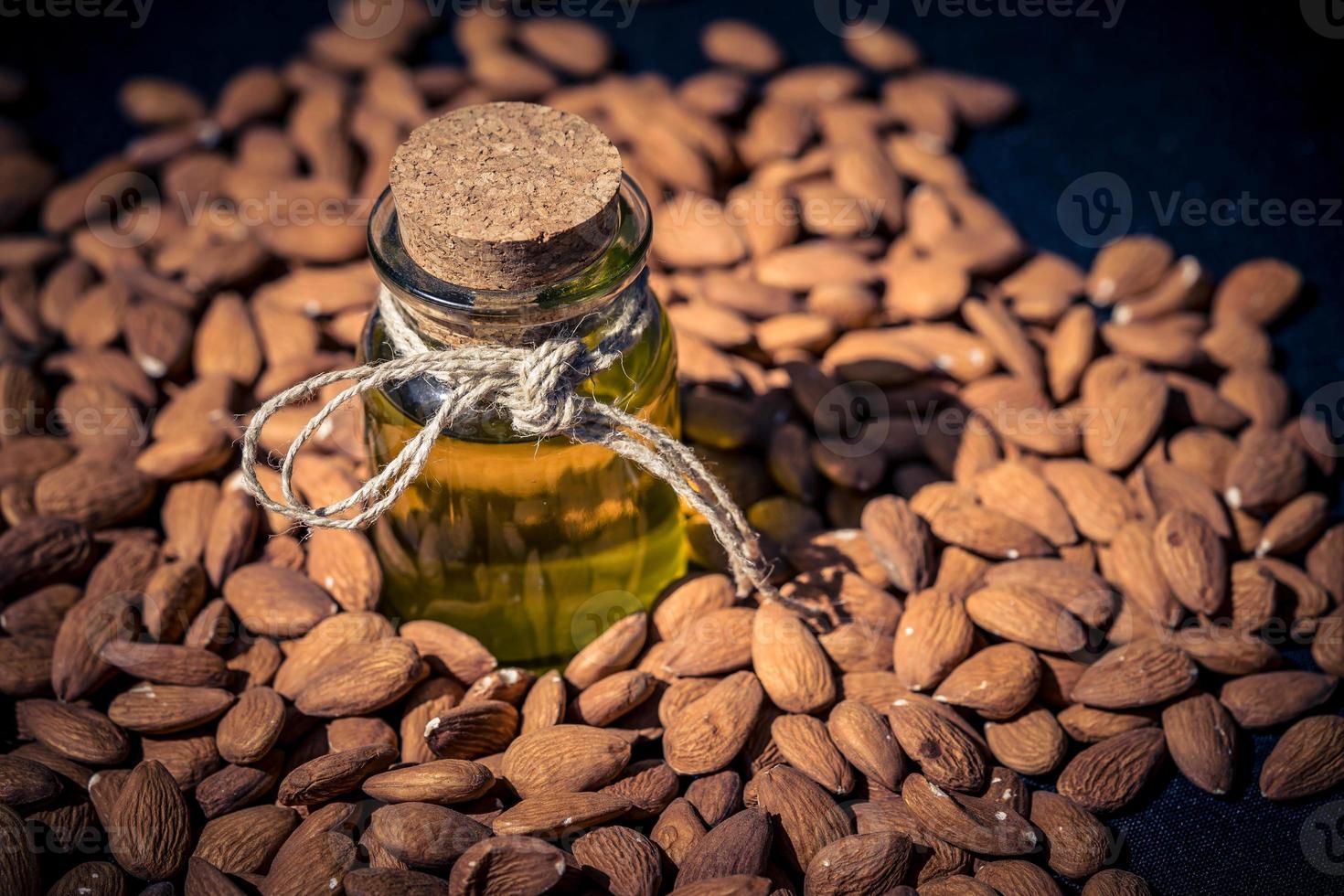 un montón de almendras y un vaso con aceite de almendras foto