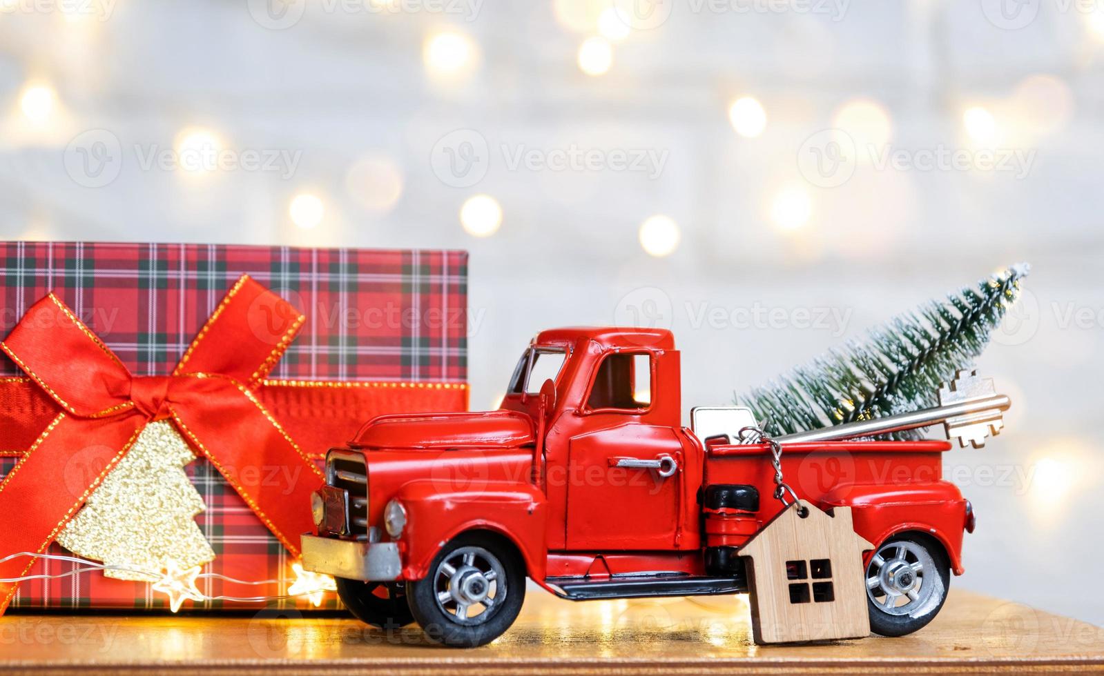 Red retro car with a Christmas tree decorates with the house key in the pickup truck for Christmas. Buying a home, moving, mortgage, loan, real estate, festive mood, New Year photo