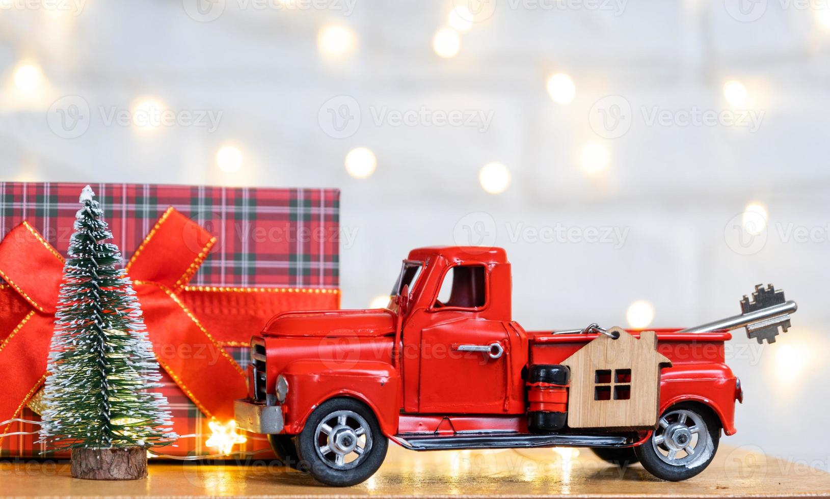 Red retro car with a Christmas tree decorates with the house key in the pickup truck for Christmas. Buying a home, moving, mortgage, loan, real estate, festive mood, New Year photo