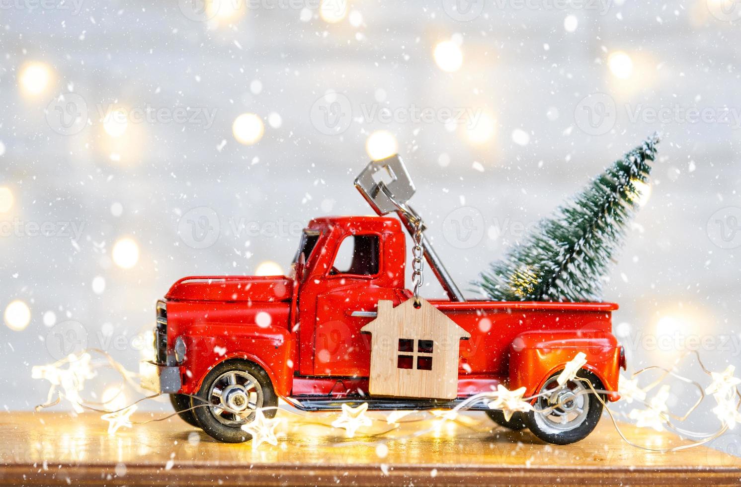 Red retro car with a Christmas tree decorates with the house key in the pickup truck for Christmas. Buying a home, moving, mortgage, loan, real estate, festive mood, New Year photo