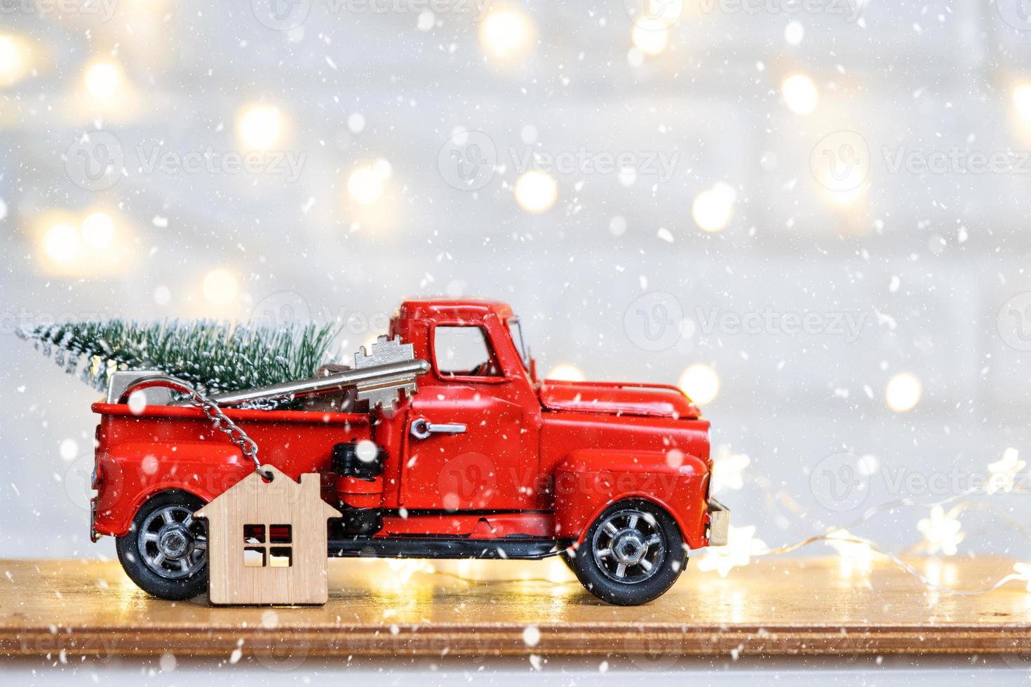 Red retro car with a Christmas tree decorates with the house key in the pickup truck for Christmas. Buying a home, moving, mortgage, loan, real estate, festive mood, New Year photo