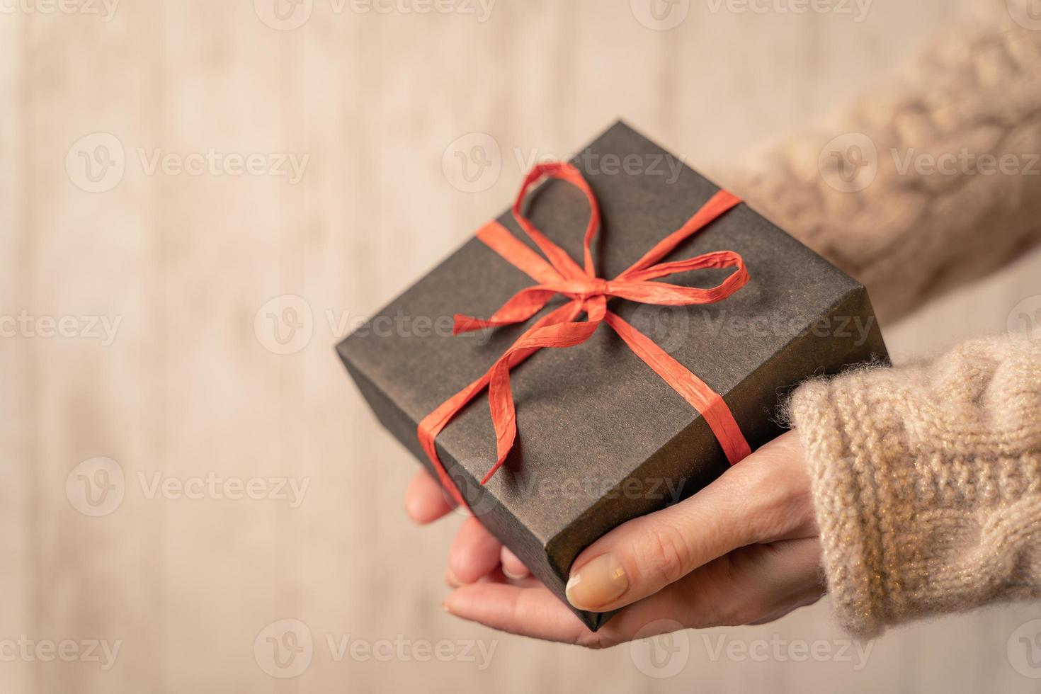 a gift box tied with a bow in women's hands, close-up,horizontal image photo