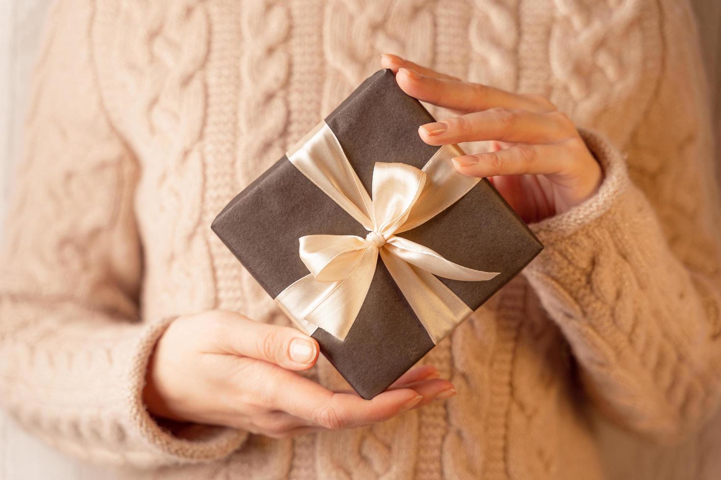 a gift box tied with a bow in women's hands, close-up,horizontal image photo