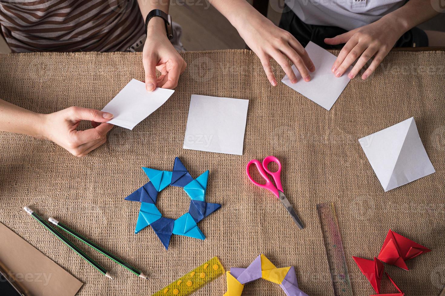 madre e hija hacen origami con papel de colores en autoaislamiento foto