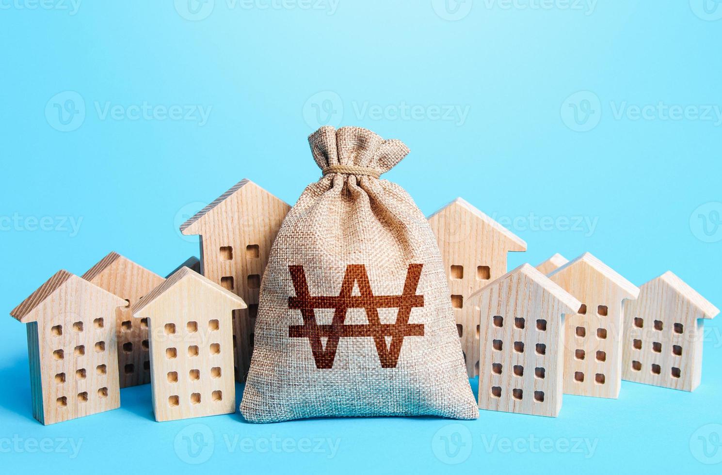 South korean won money bag among town houses figurines. Rich city. Rental business. Realtor services. Sale of real estate. Taxes. Tax collection, investment in city development. Municipal budgeting. photo