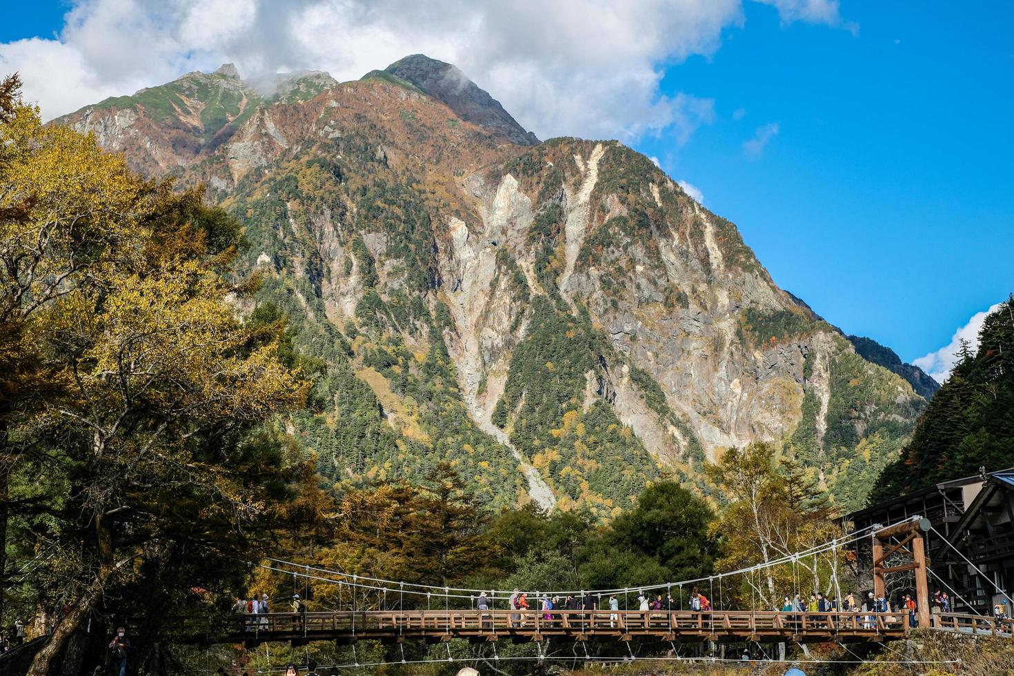 kamikochi, nagano, japón - octubre de 2022 turistas no identificados disfrutan en el puente kappa bashi en el área del punto central del parque nacional kamikochi durante la temporada de follaje de otoño. foto